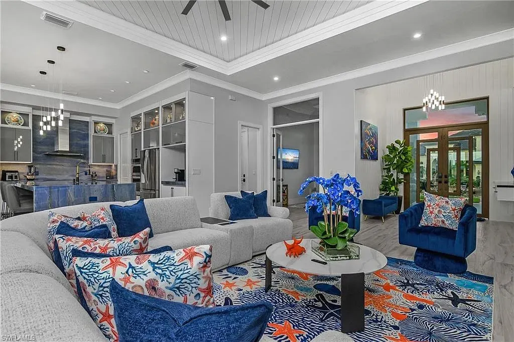 Open living area with a blue stone-look kitchen island, glass-front cabinets and a glass entry door beyond.
