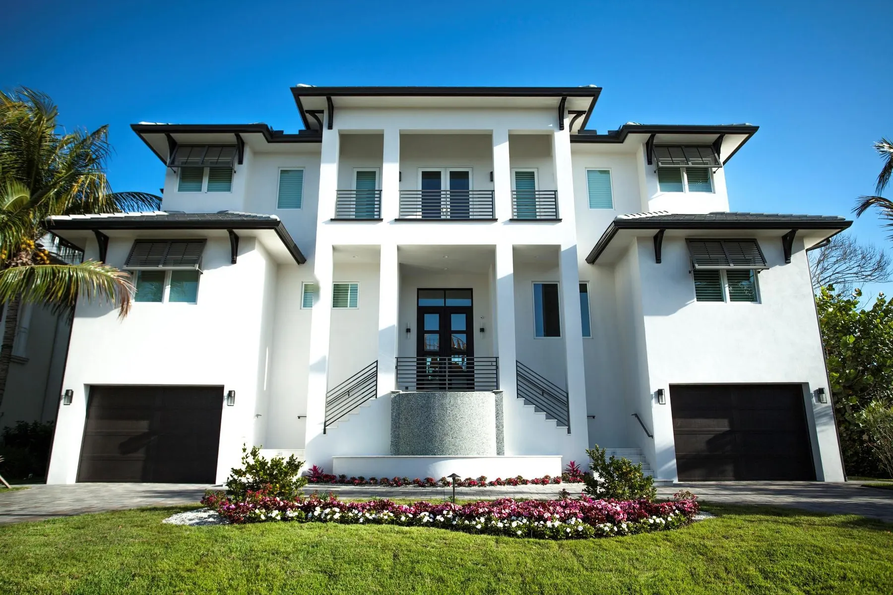 Front elevation of the three-story white coastal residence with columns, balconies and a central water feature.