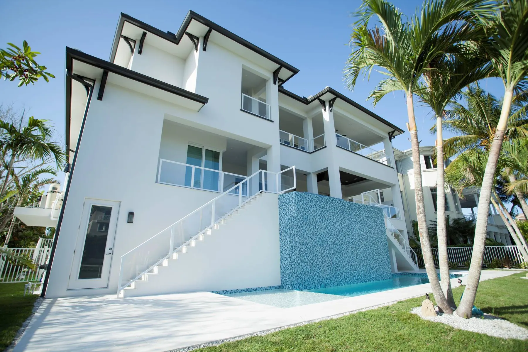 Side view of the rear elevation with a glass-tile water feature wall, white stair and pool edge.