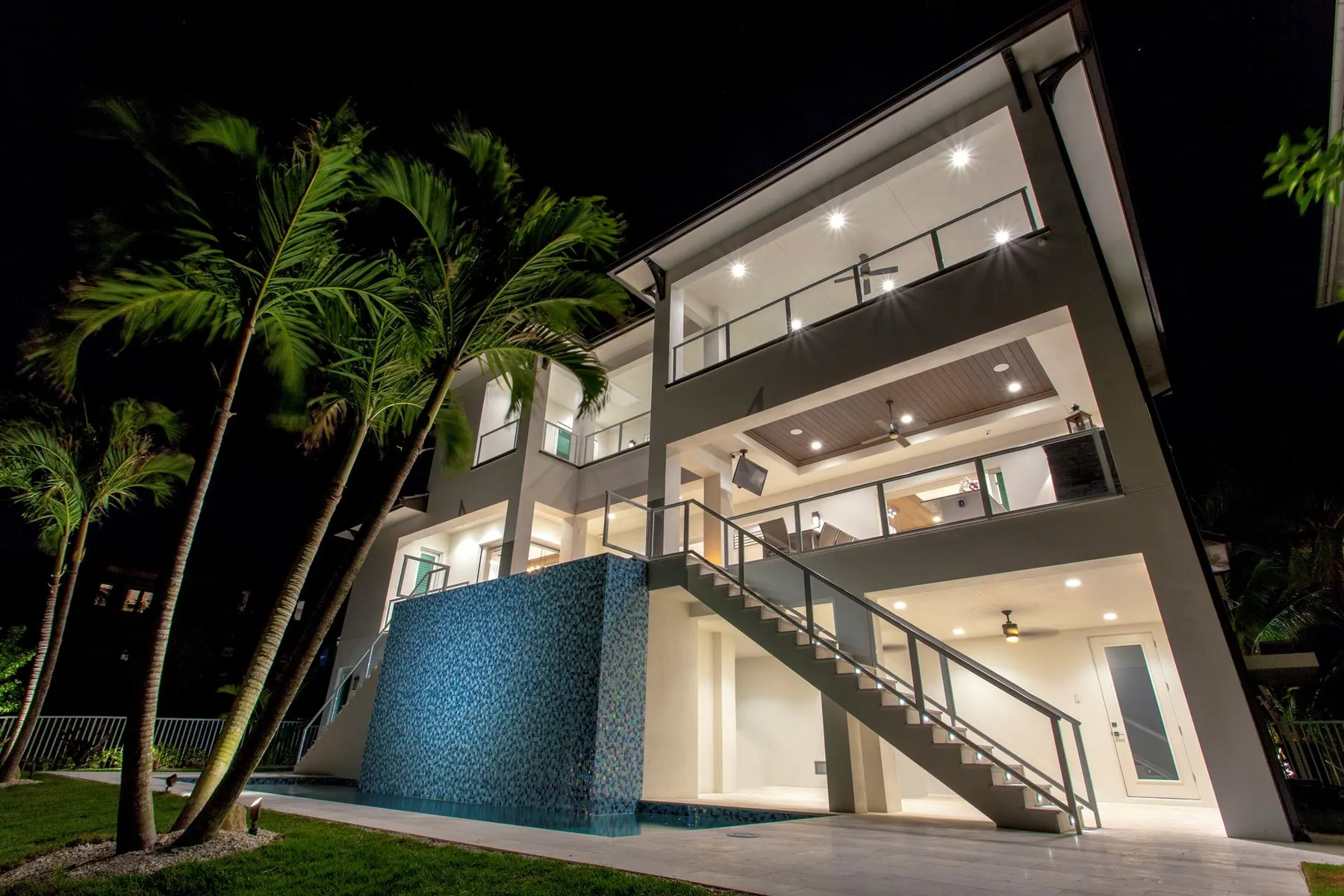 Rear terraces and glass-tile water feature at night.