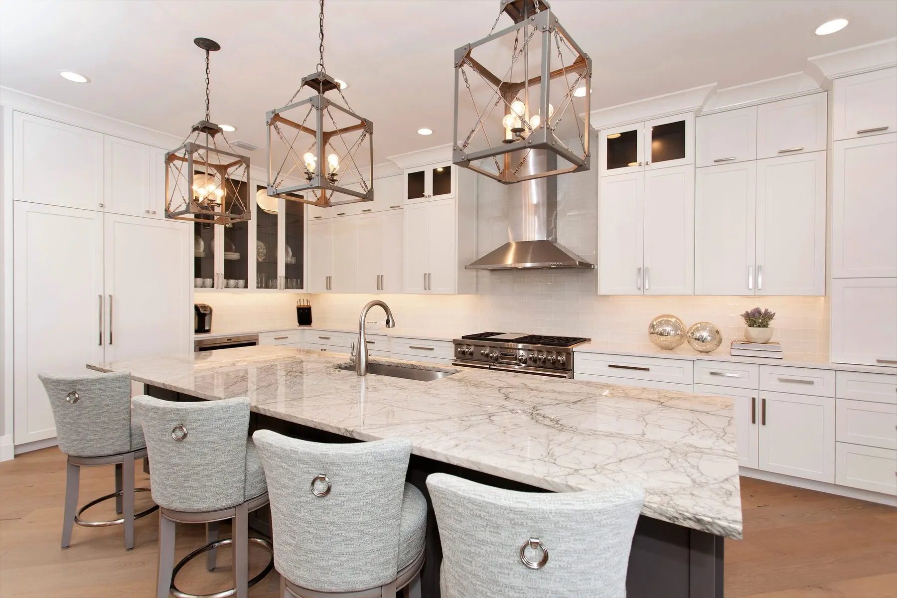 Kitchen island with upholstered counter stools and lantern pendants.