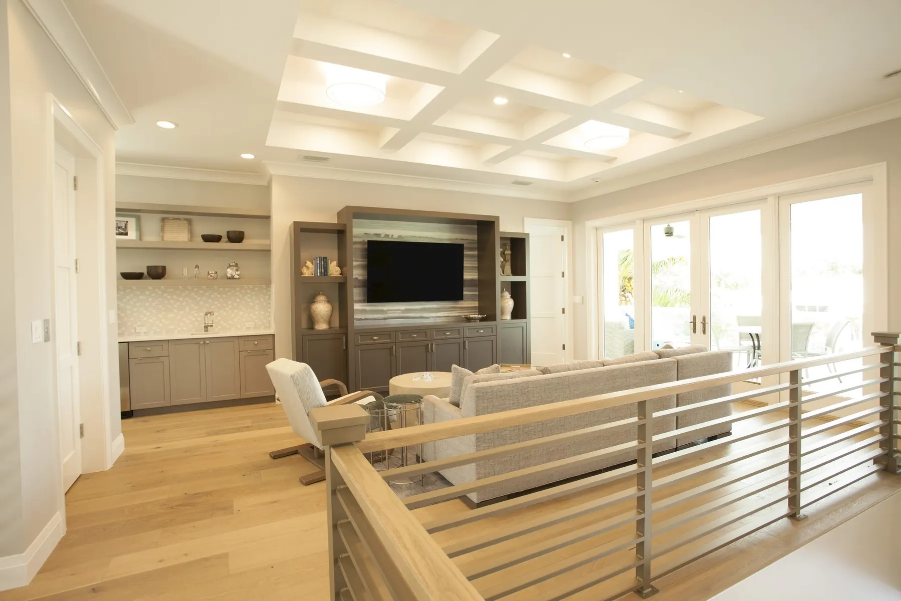 Upper-level lounge with a built-in media wall and glass doors to the terrace.