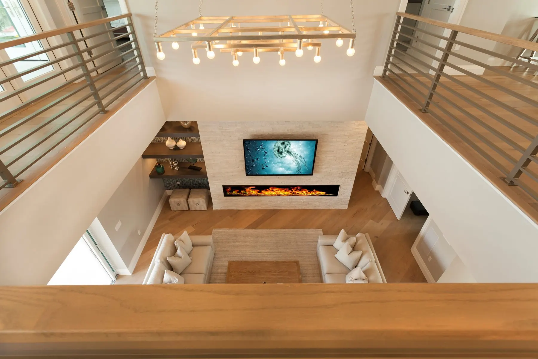 View down from the stair railing to a sunken lounge with a linear fireplace.