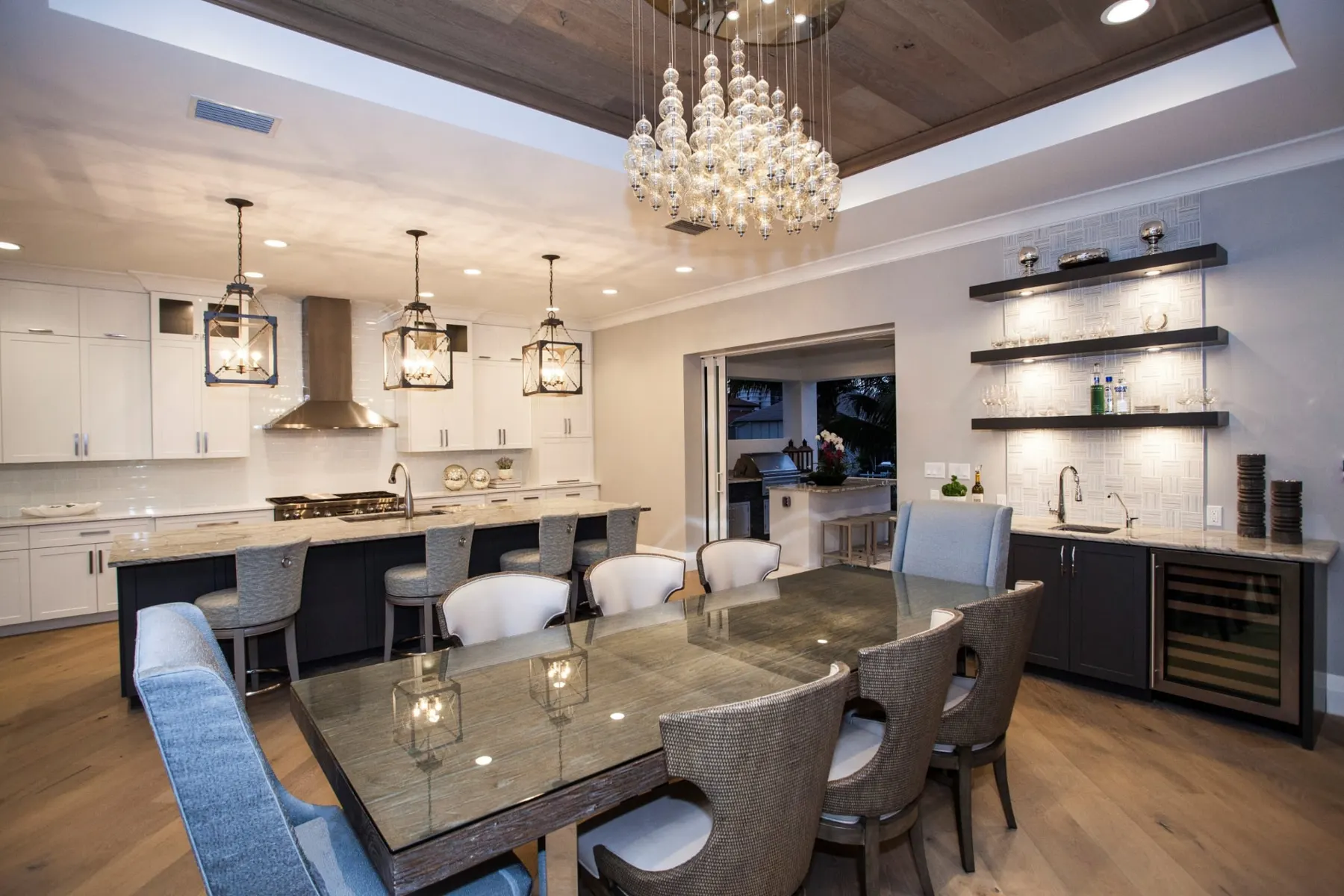 Kitchen and dining area with a crystal chandelier and floating wood shelves.