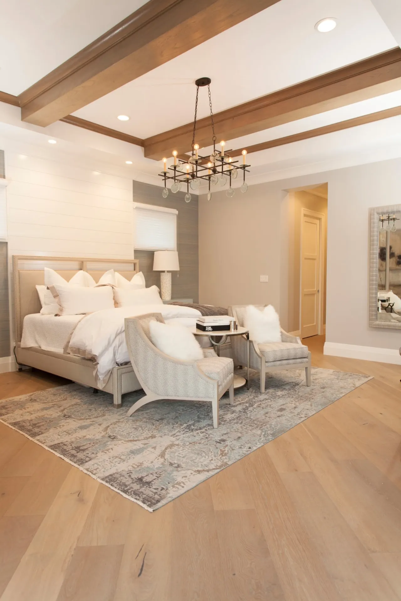 Bedroom with a beamed ceiling, chandelier and seating area.