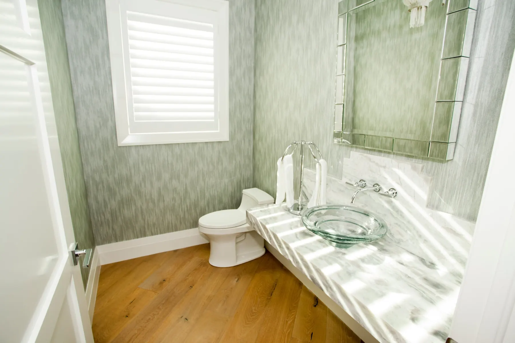 Powder room with textured wallpaper and a glass vessel sink.