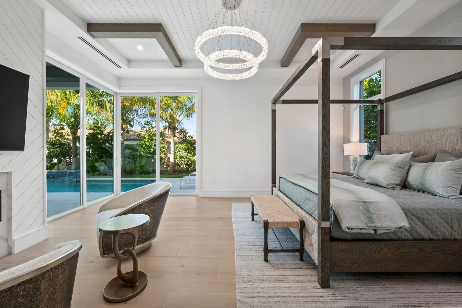 Primary bedroom with a four-post canopy bed, a ring chandelier and sliding doors to the pool.