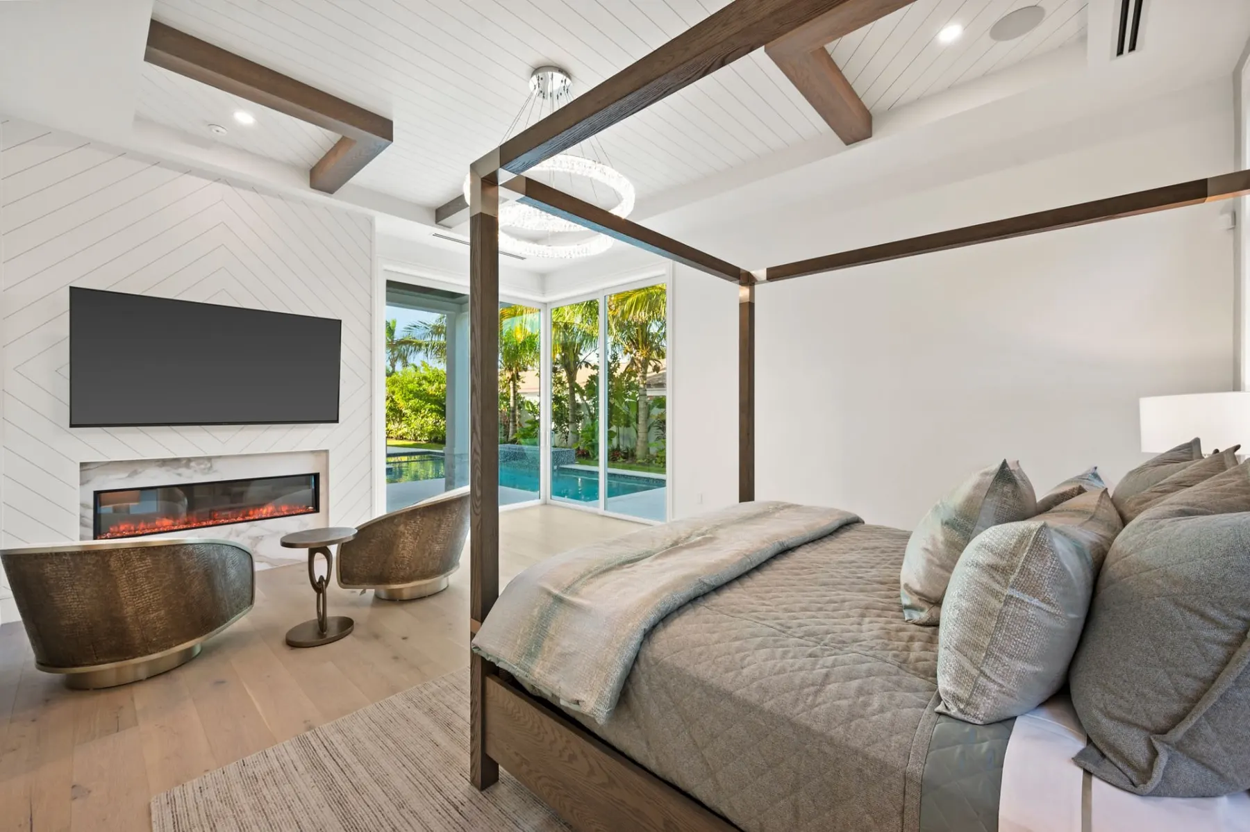 Primary bedroom with a canopy bed, a linear fireplace and a wall-mounted television.