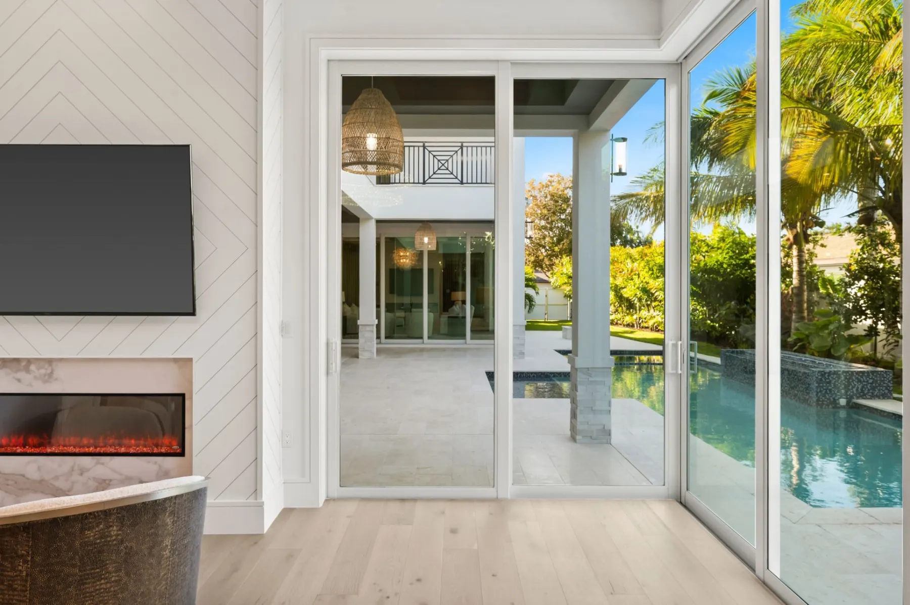 Primary bedroom fireplace wall with glass doors opening to the covered terrace and pool.