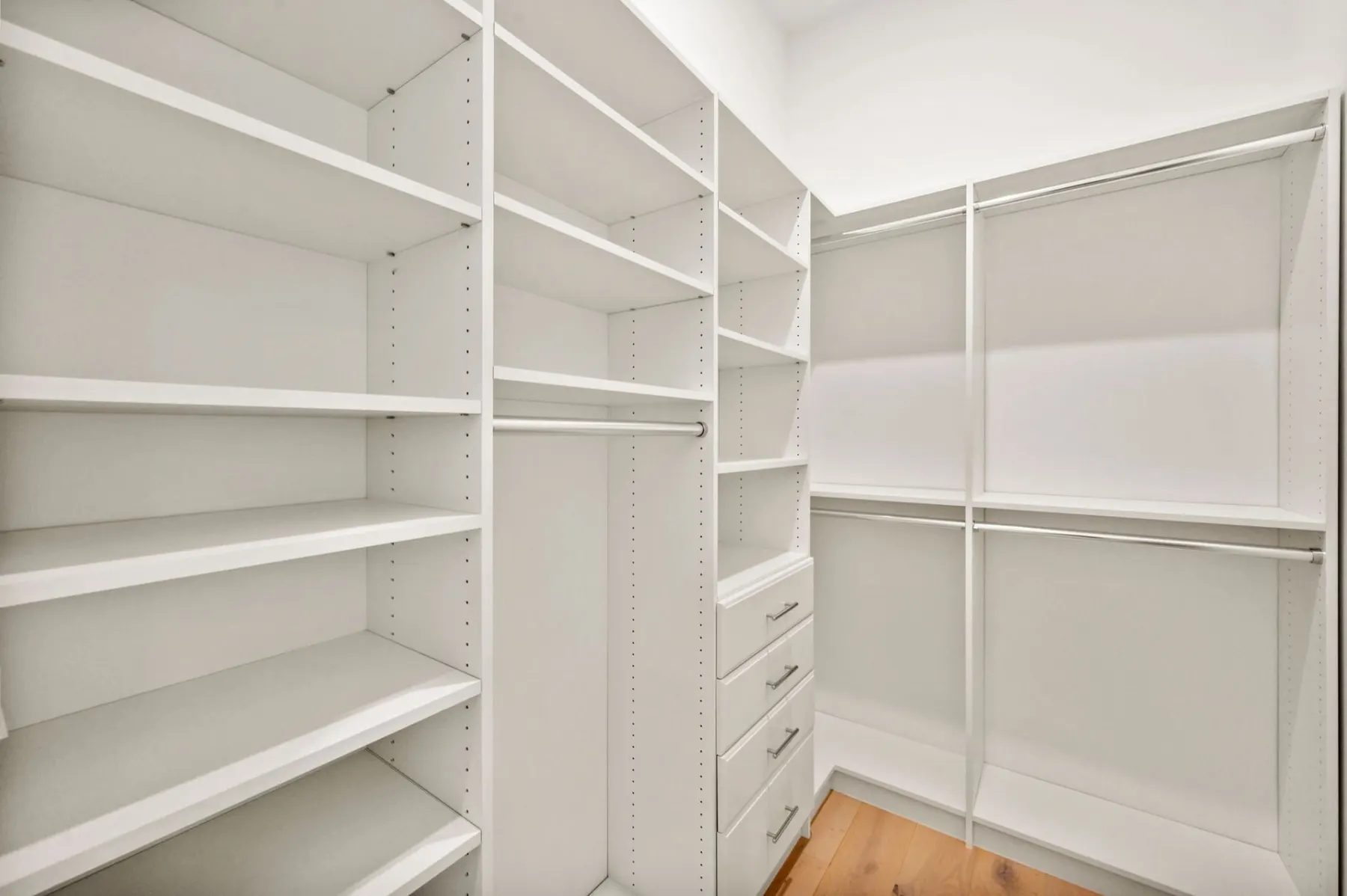 Primary closet with adjustable shelves and drawers along the corner walls.
