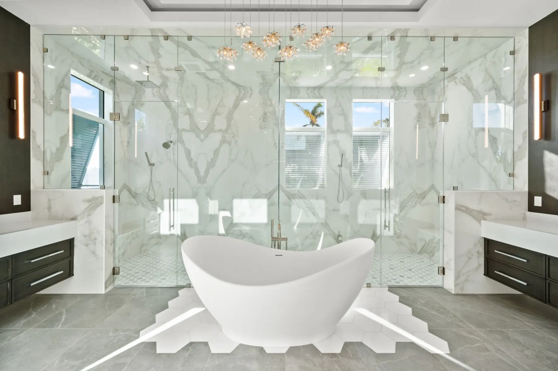 Primary bath with a freestanding tub in a glass-enclosed shower area with white veined tile and a pendant above.
