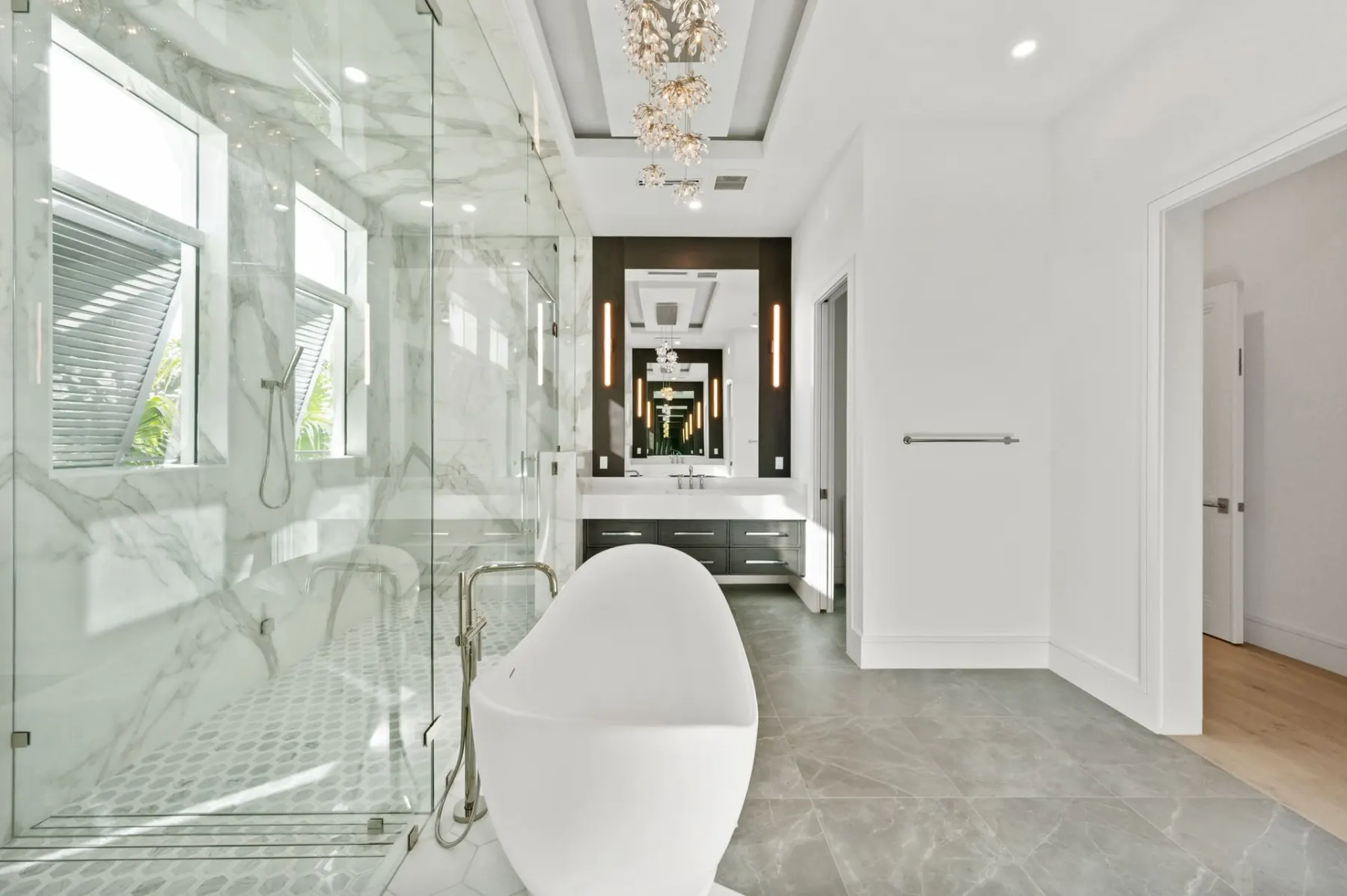 Primary bath with a freestanding tub, a glass shower and a floating vanity with a mirror beyond.