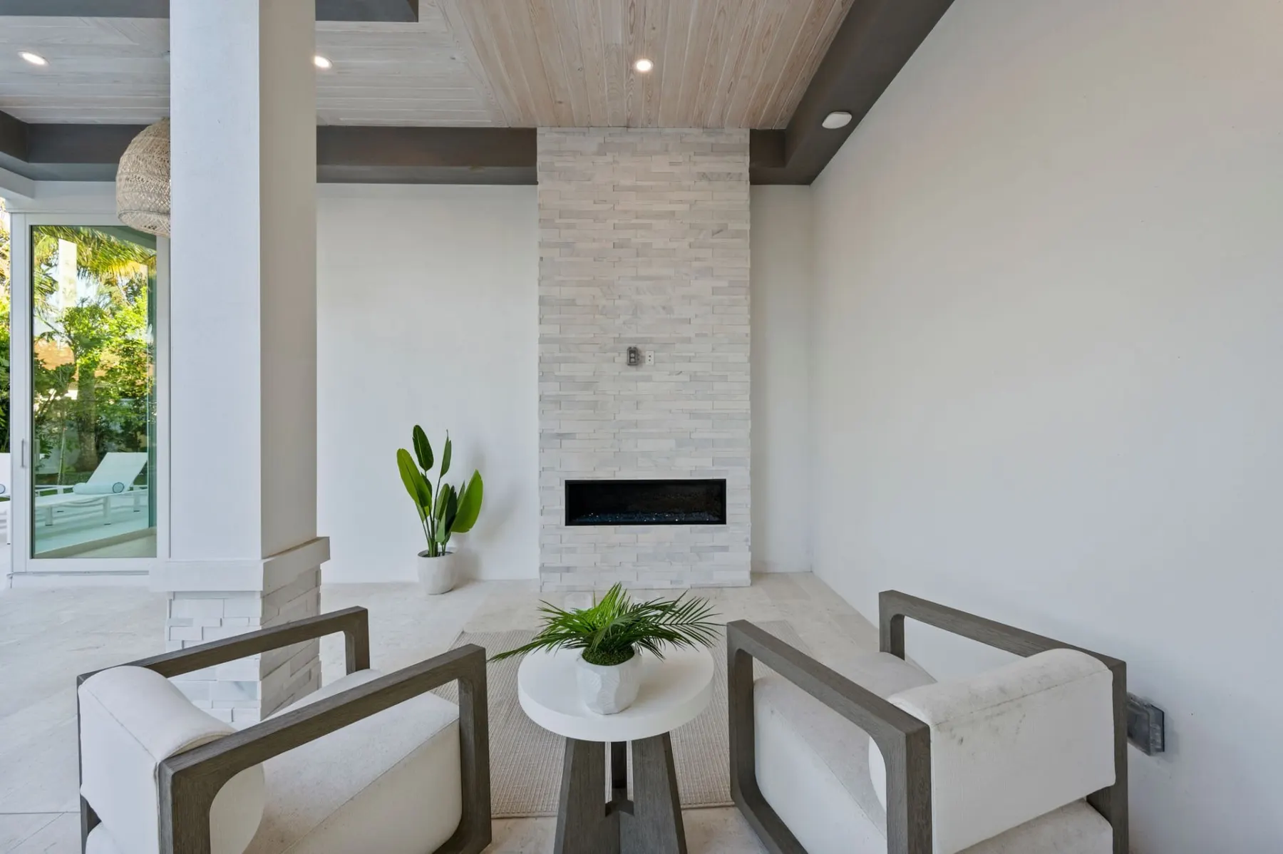 Lanai seating beside a stacked-stone linear fireplace.