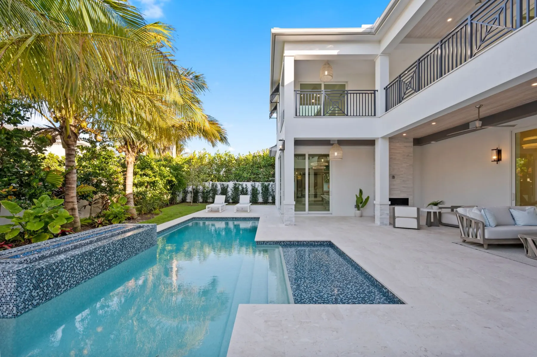 Pool with a mosaic tile step, a raised spa and the covered lanai seating in the background.