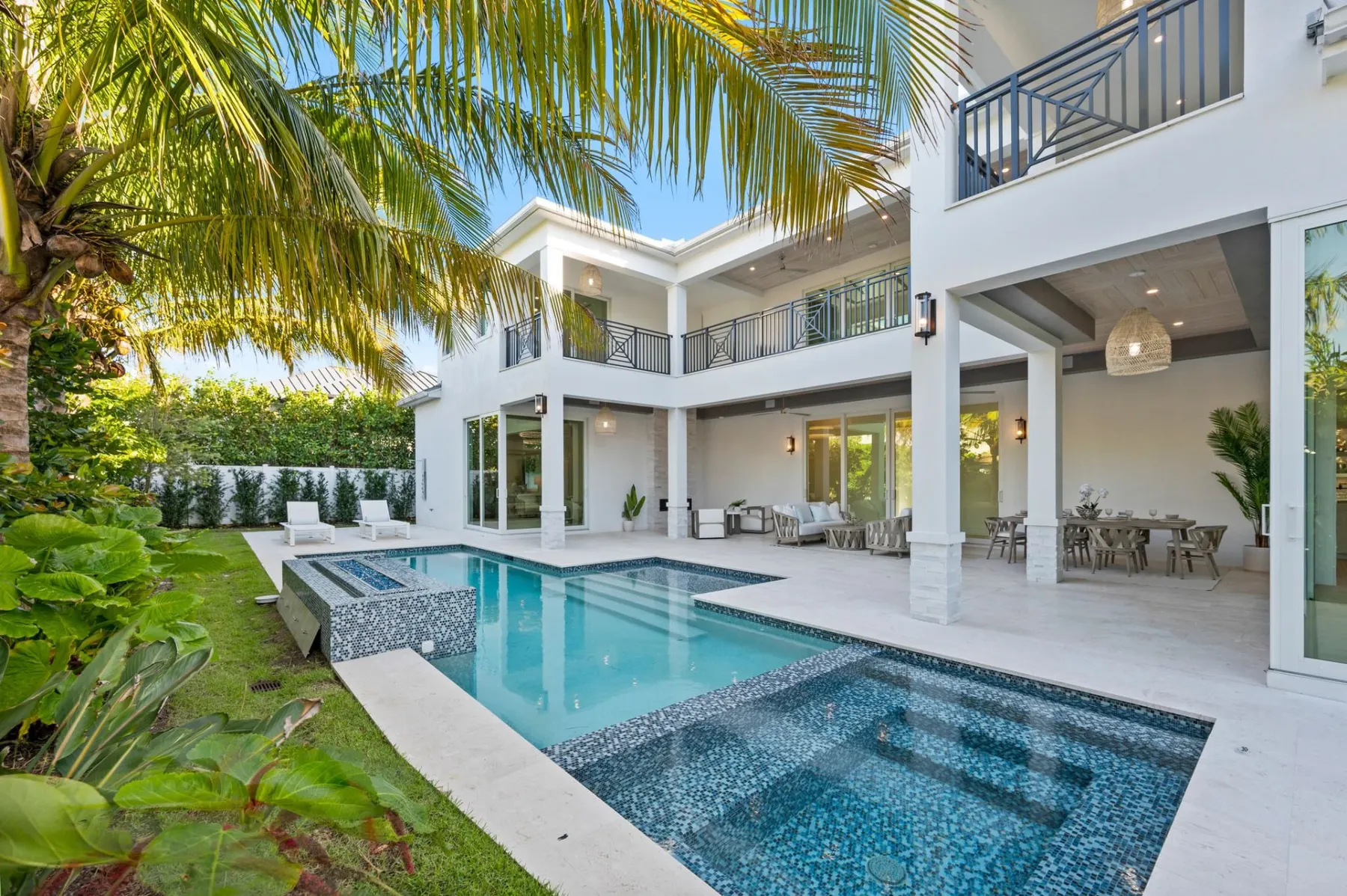 Pool and spa below the rear balconies and the covered lanai with a dining table.
