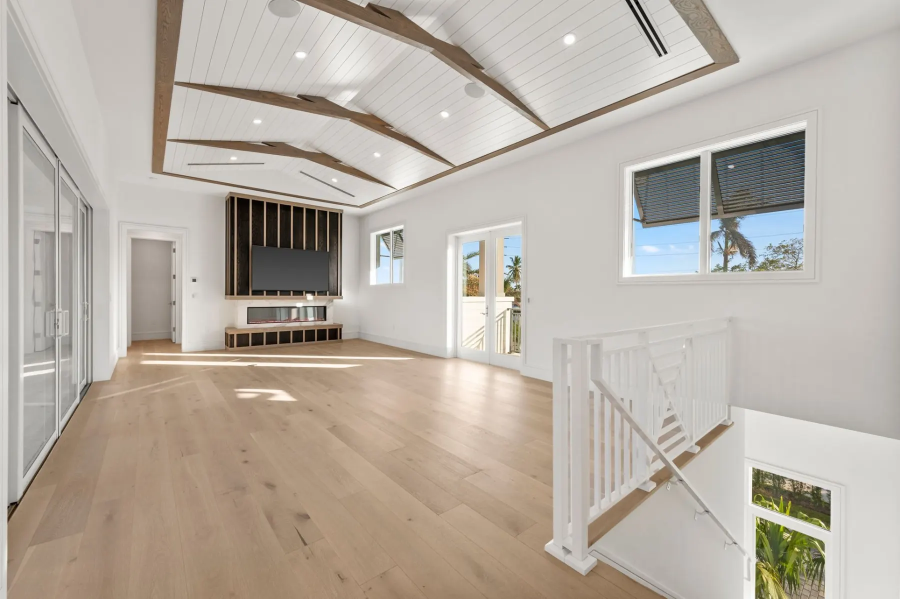 Upstairs lounge with a media wall, a planked ceiling with wood trim and a white stair railing.