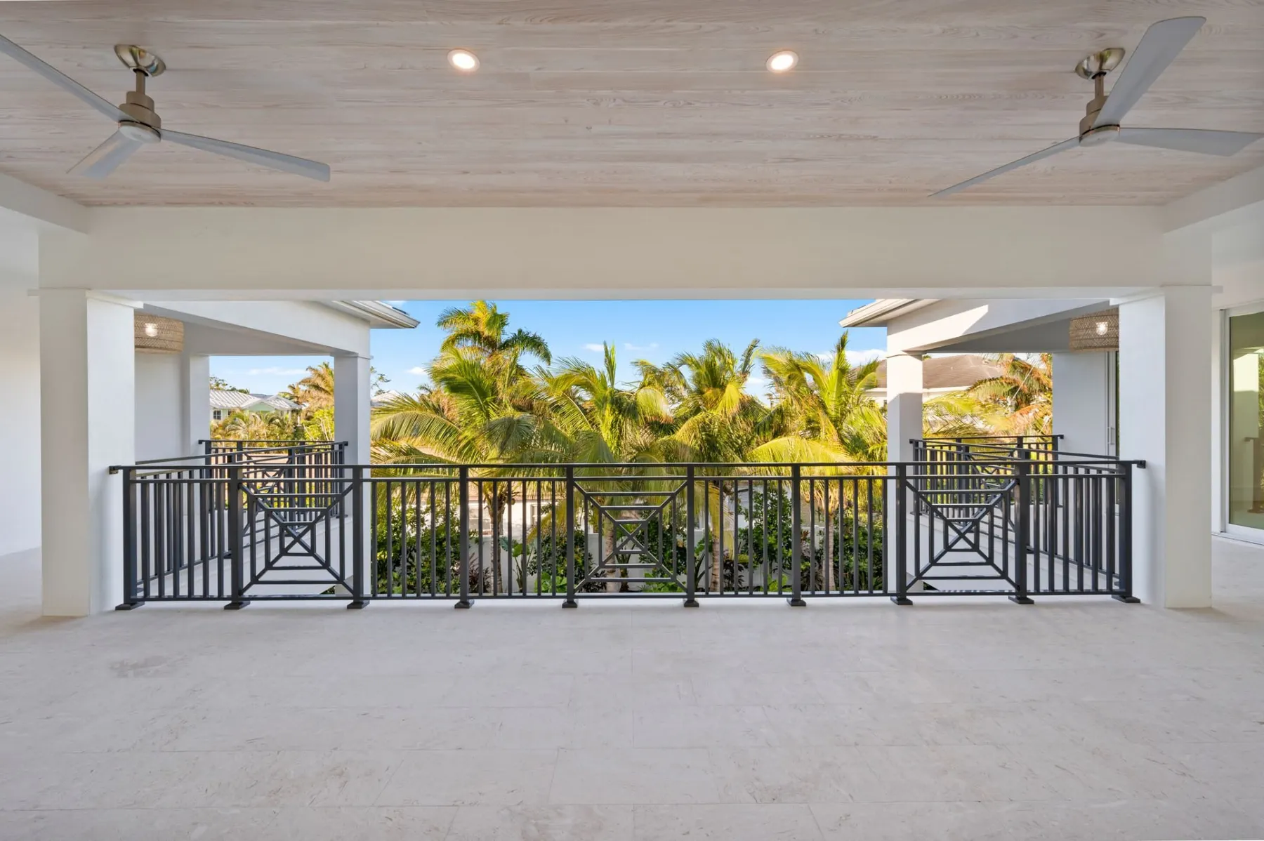 Upstairs covered balcony with a black railing and ceiling fans.
