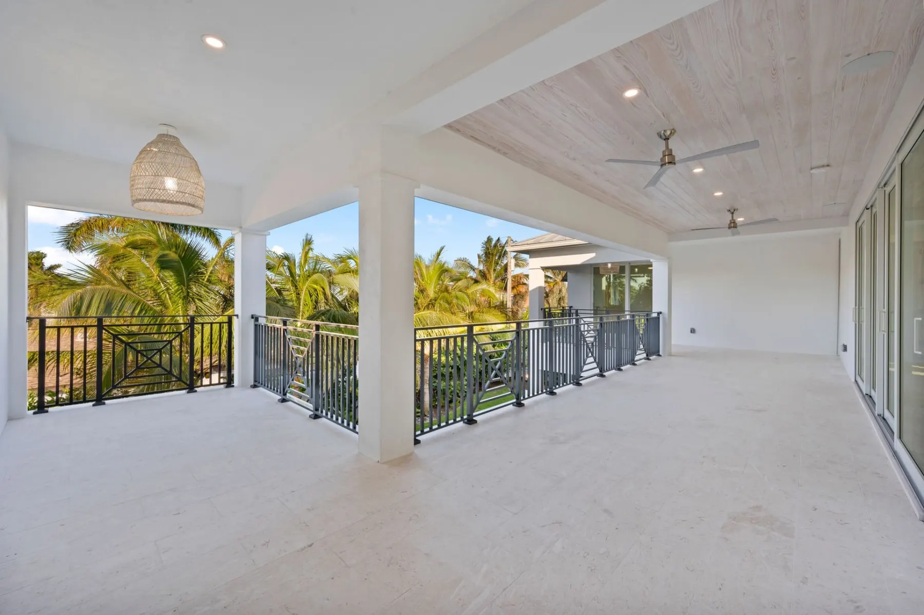 Upstairs covered balcony with a woven pendant light, a railing and a view of the trees.