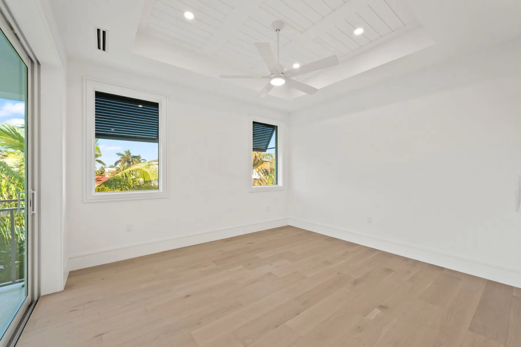Upstairs bedroom with a tray ceiling, a ceiling fan and two windows.