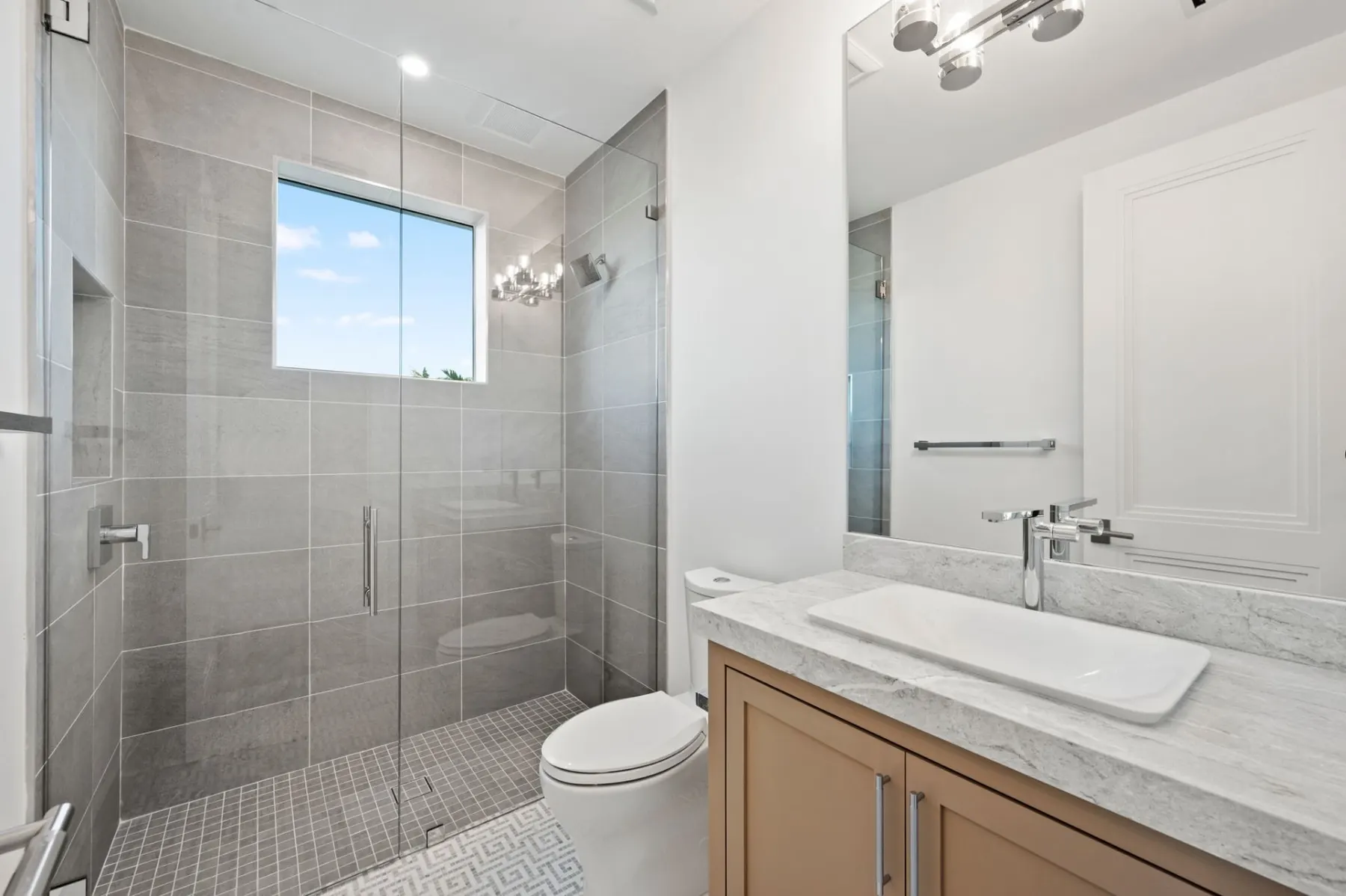 Bath with a gray tile shower, a vessel sink and a wood vanity.