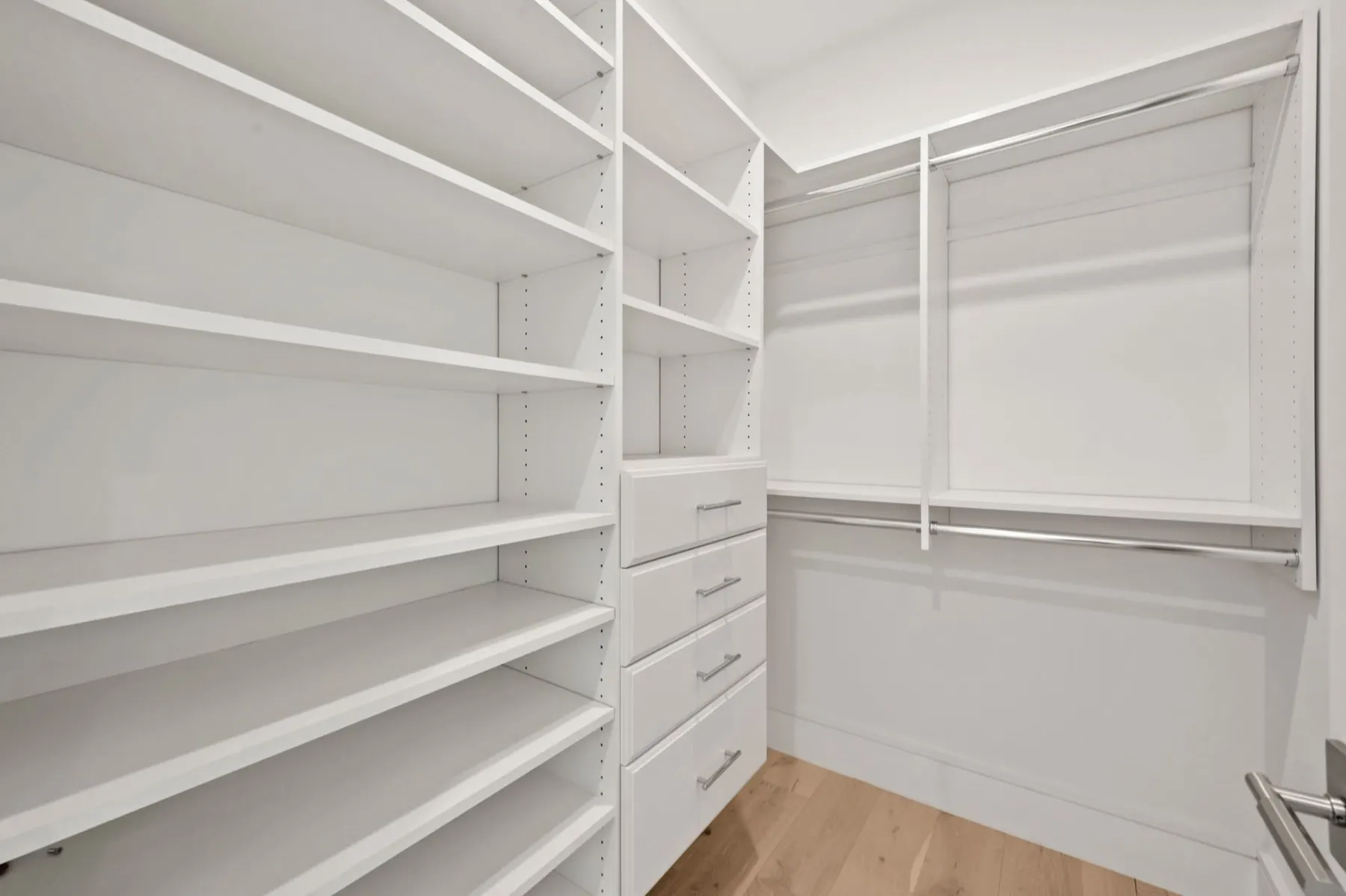 Walk-in closet with white shelving and drawers.