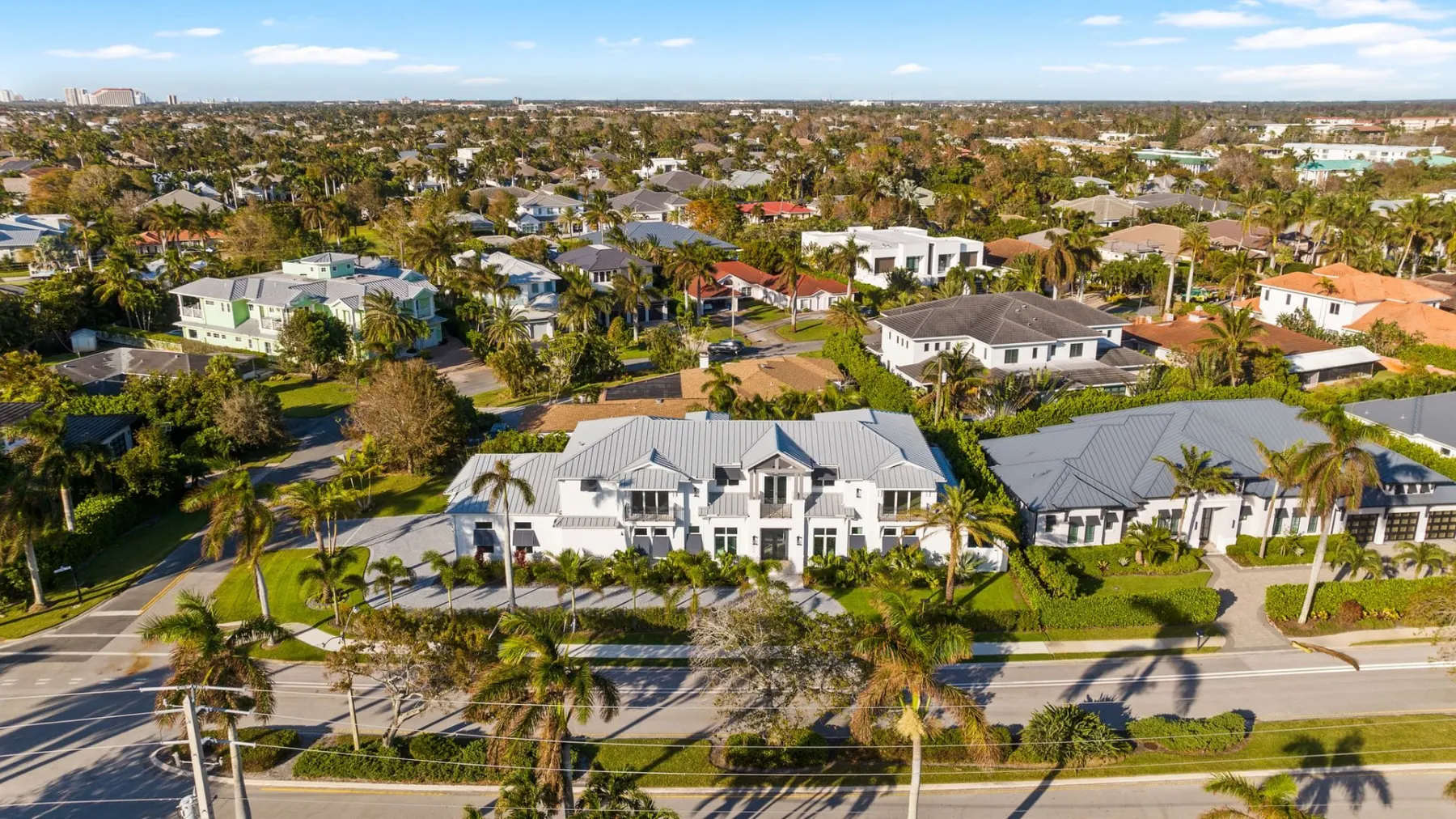 Wide aerial view of the home among neighboring houses and tree-lined streets.