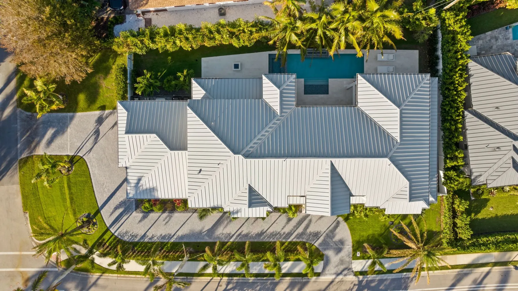 Overhead aerial view of the standing-seam metal roof, with the pool visible behind the home.