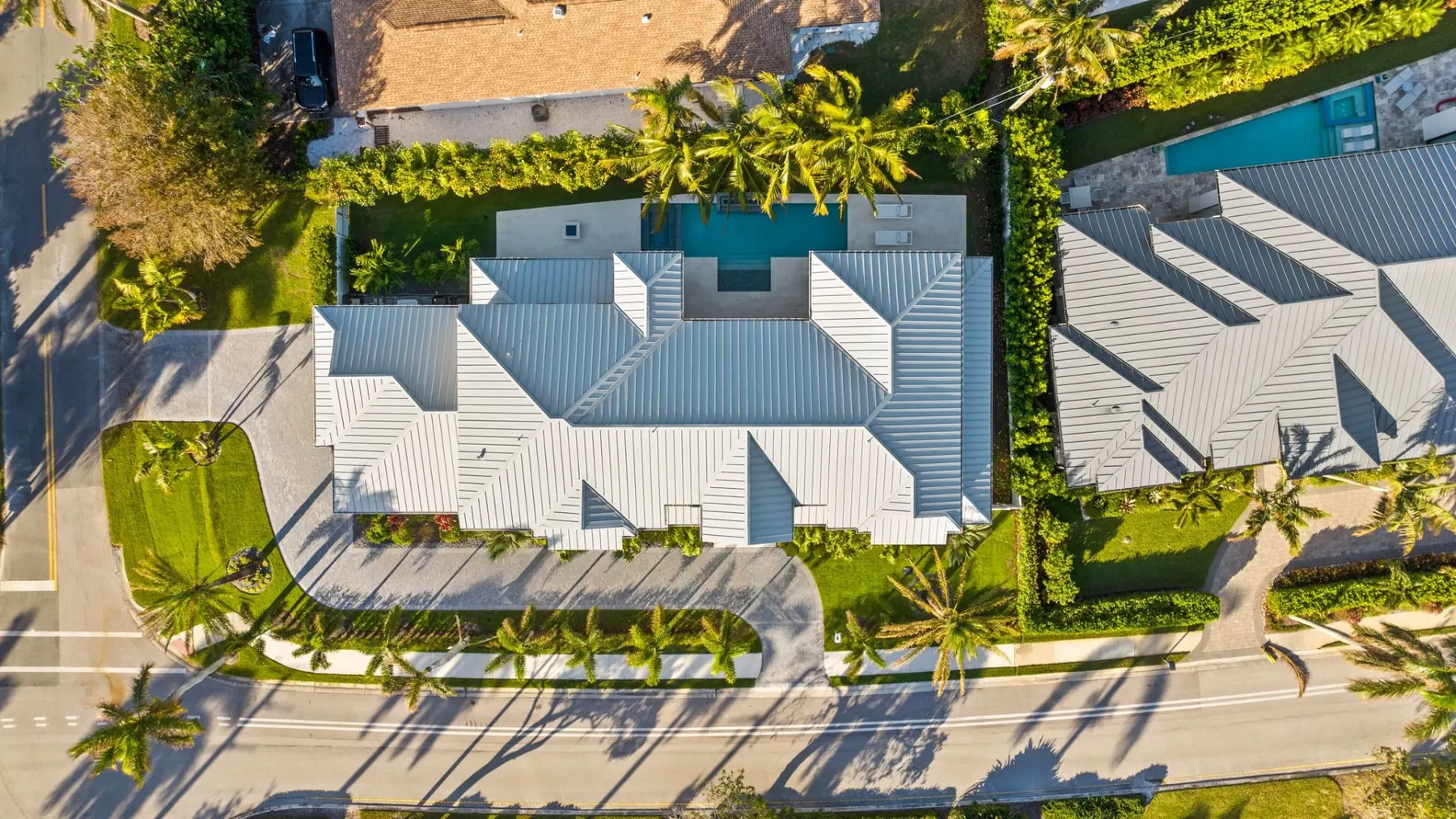 Overhead aerial view of the roof and lot, with the curved driveway at the front and the pool at the rear.