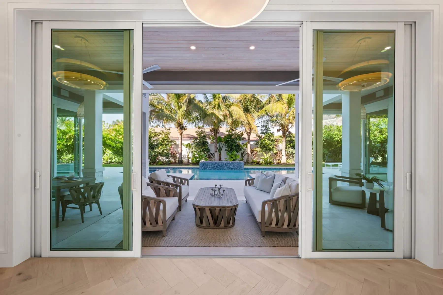 Sliding glass doors open to the covered lanai seating area, with the pool and spa beyond.