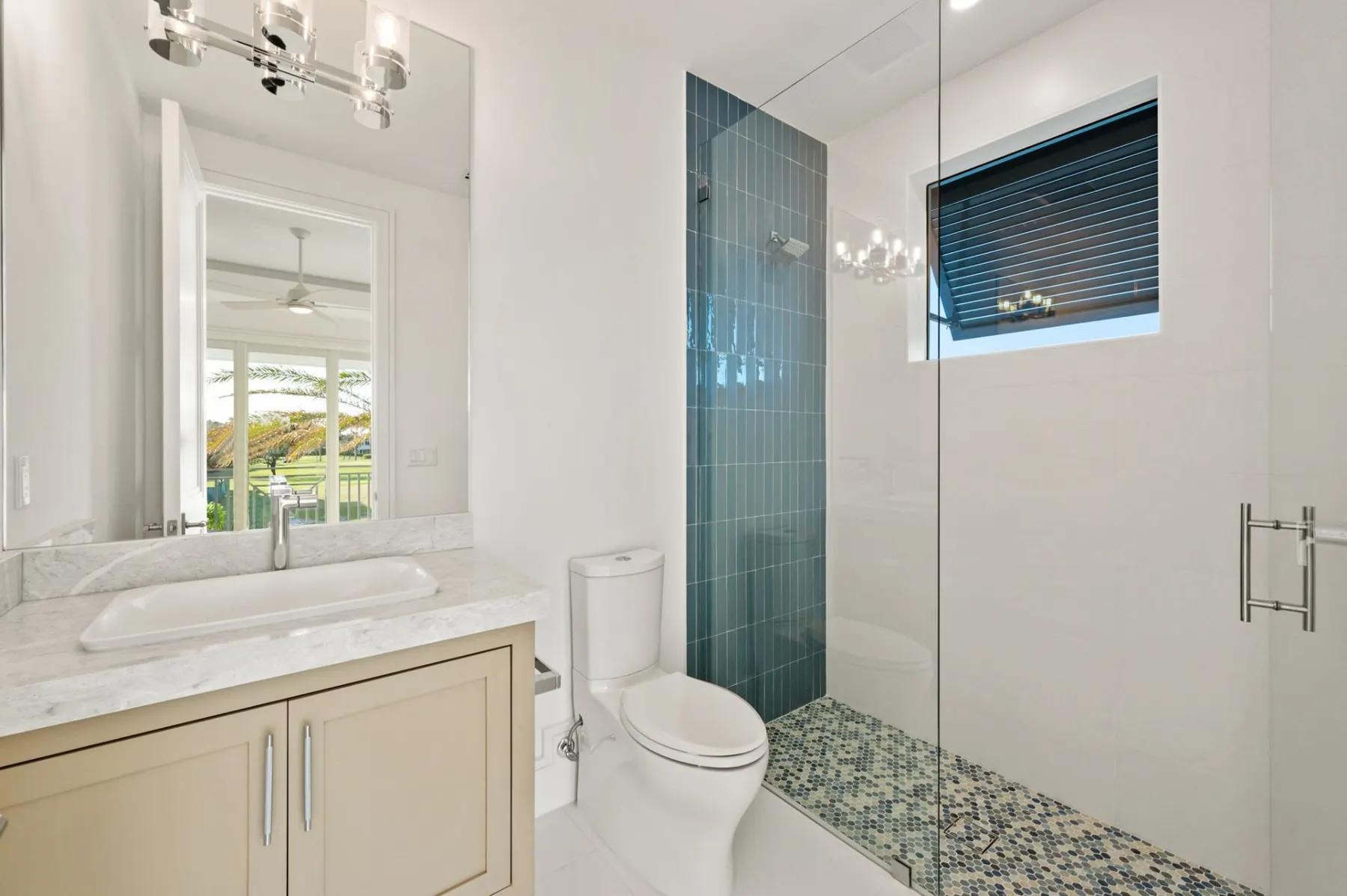 Bath with a vertical blue tile accent, a drop-in sink on a cream vanity and a glass-enclosed shower.