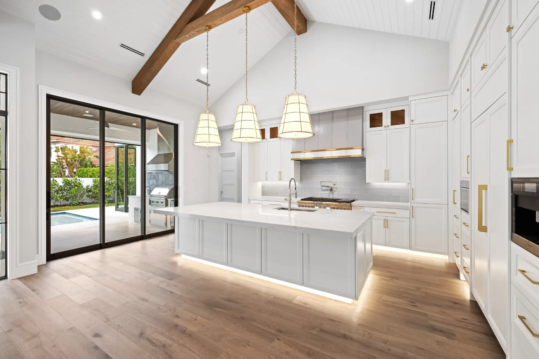 Kitchen island with under-cabinet lighting, white cabinetry and sliding glass doors to the lanai.