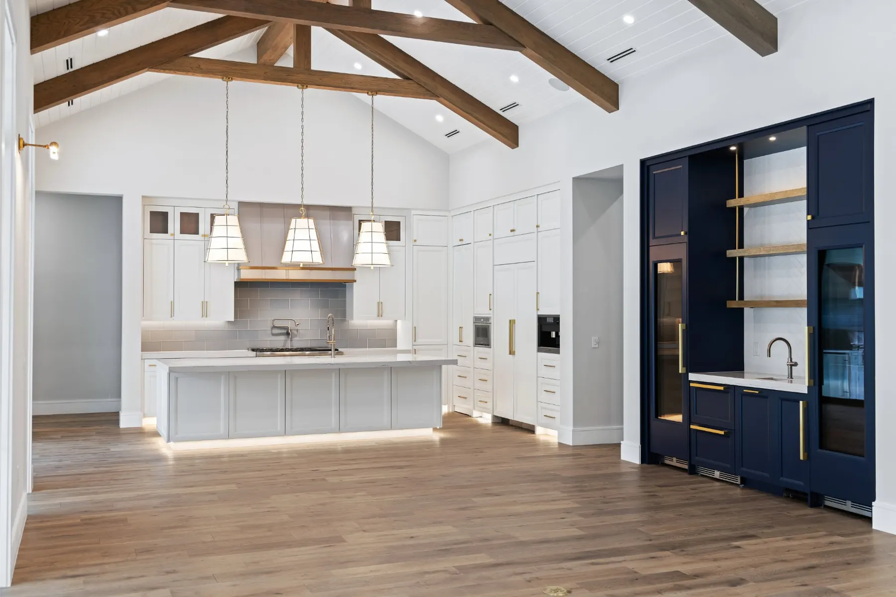 Kitchen with a navy bar cabinet, woven pendants and timber trusses overhead.