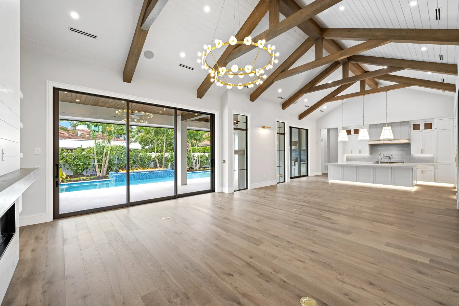 Great room with a brass ring chandelier and sliding glass doors to the covered lanai and pool.