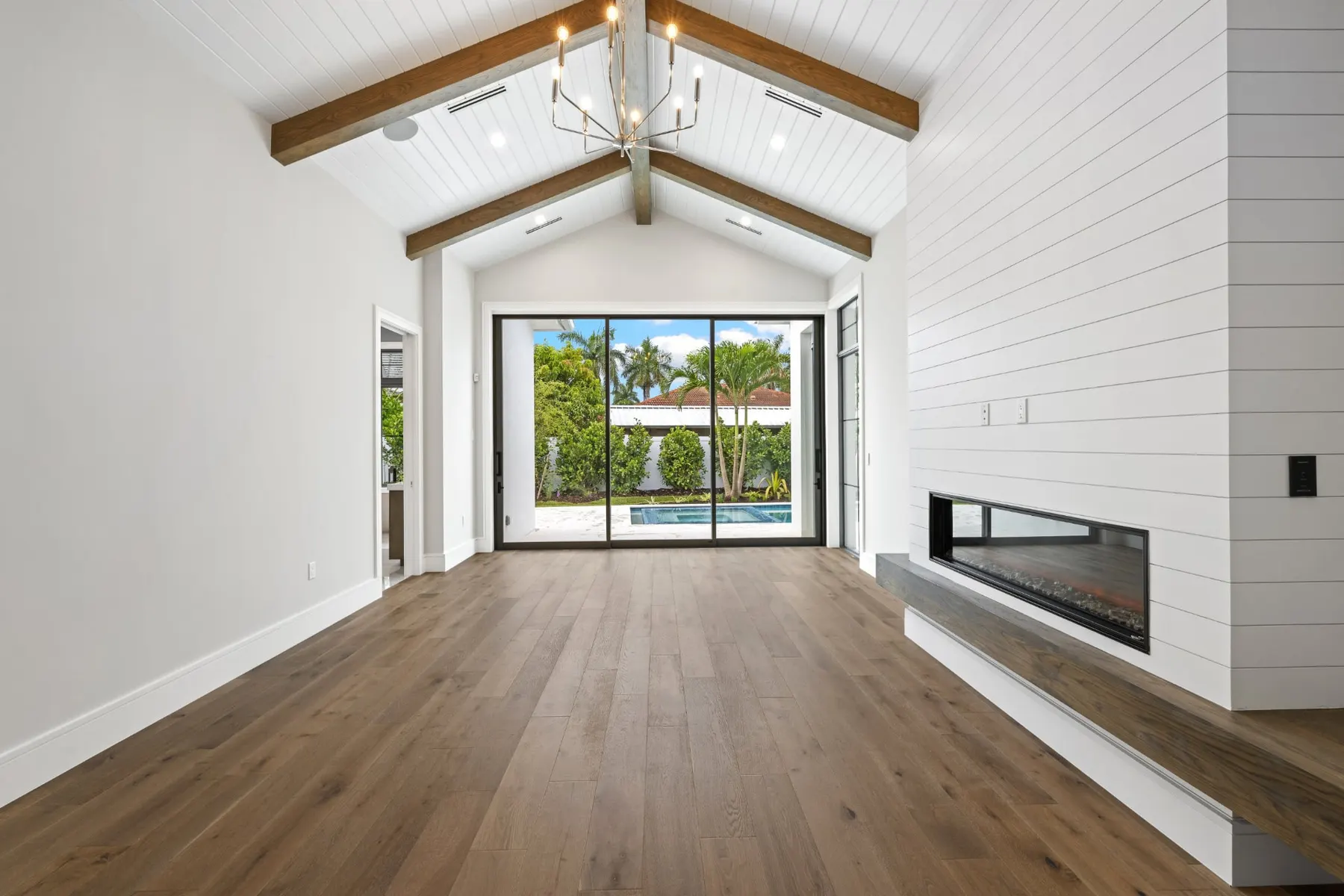 Living room looking along the linear fireplace toward sliding glass doors to the pool.