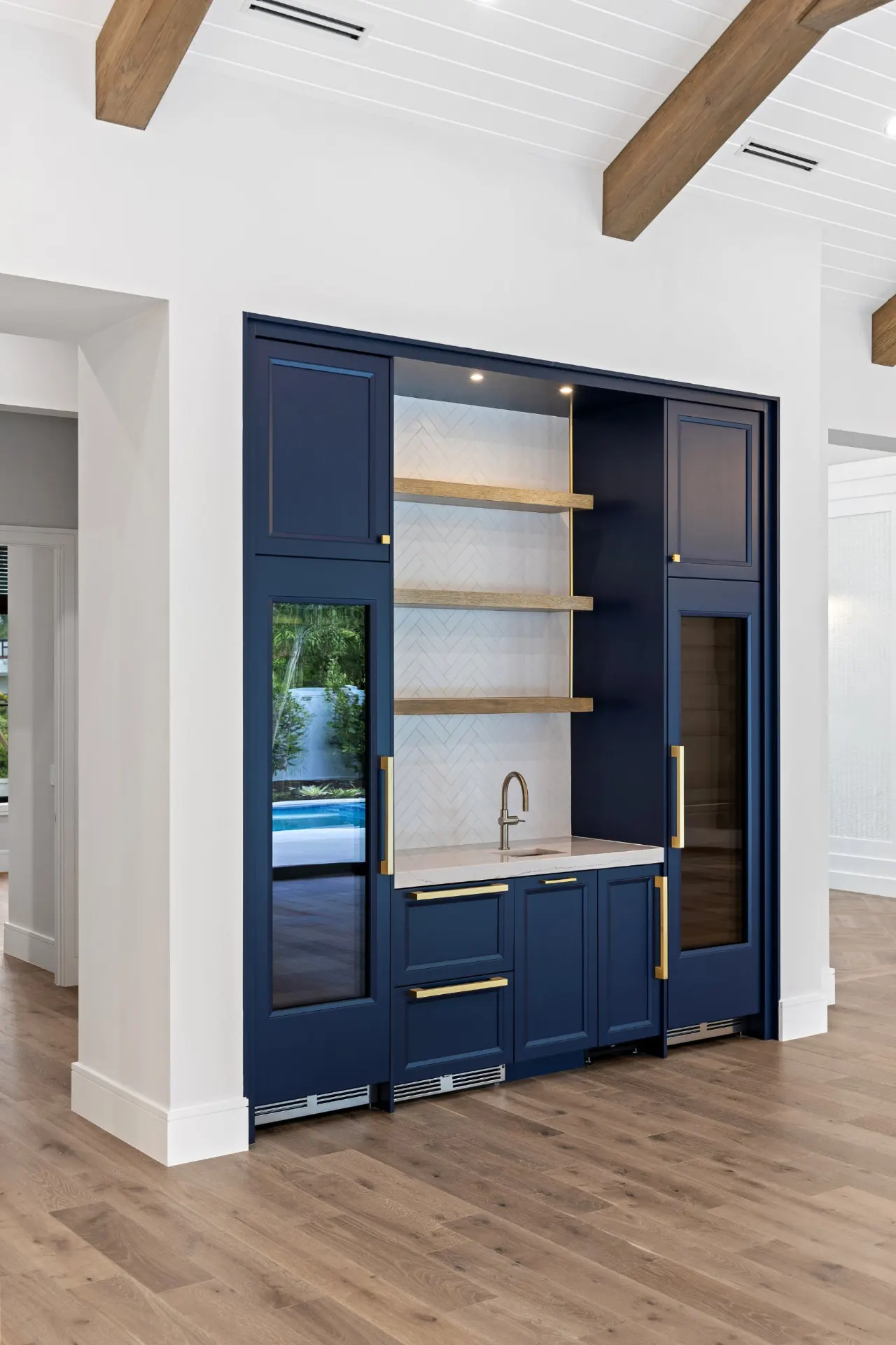 Portrait view of the navy bar and beverage coolers with the glass entry doors beyond.