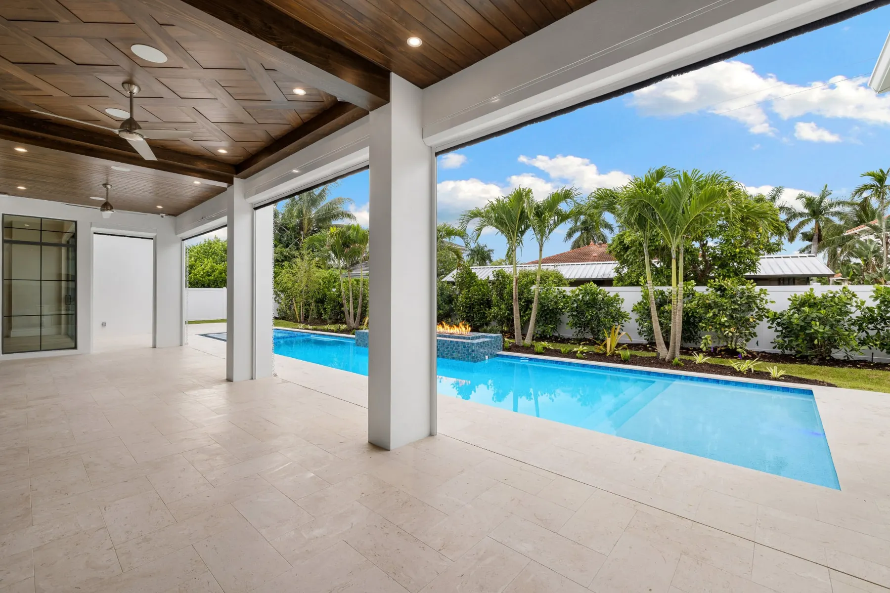 Covered lanai with a patterned wood ceiling looking across the pool.