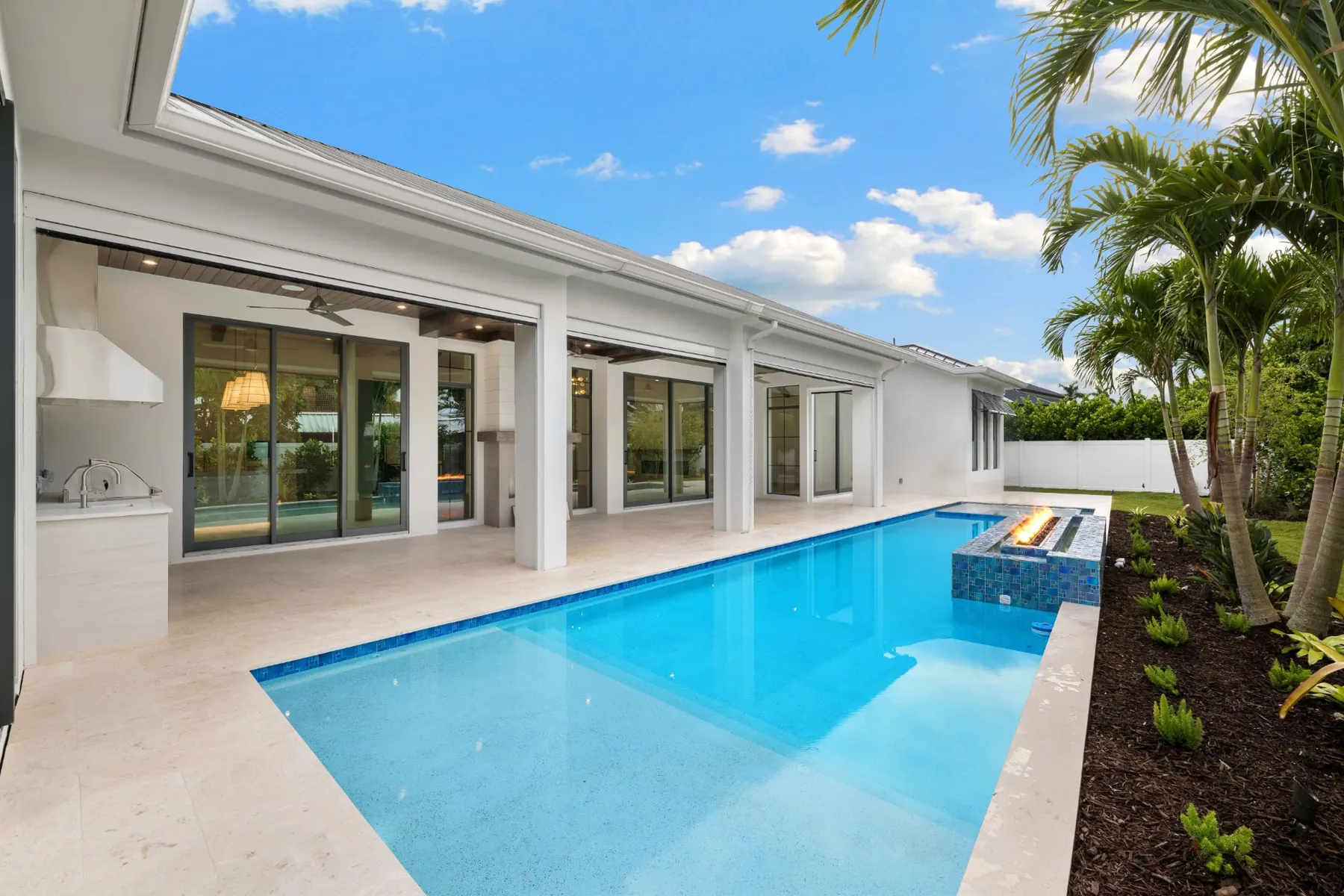Pool and lanai in daylight from the garden end, with the outdoor kitchen at left.