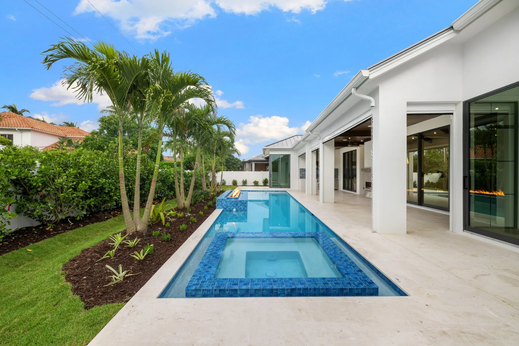 Pool and spa from the side with palms and the covered lanai beyond.