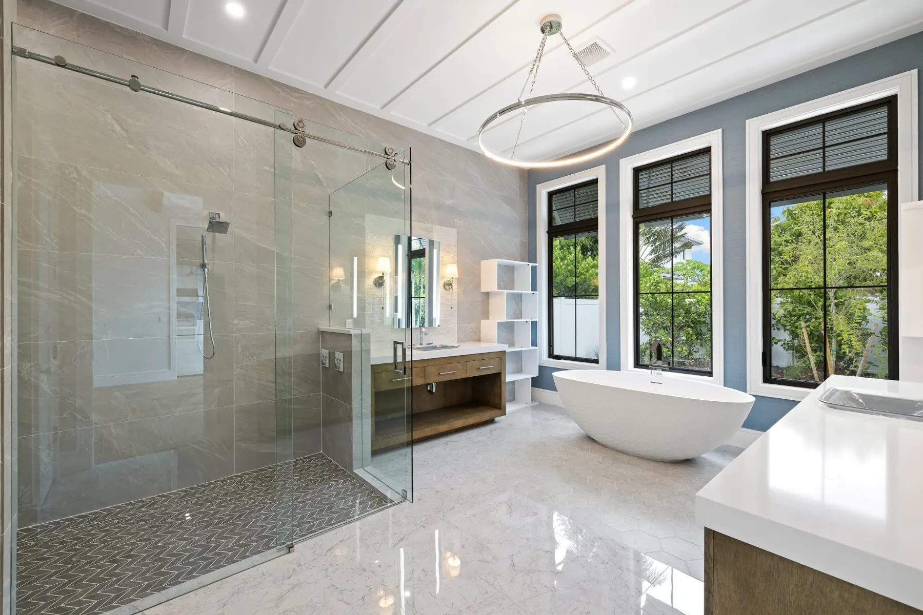 Bath with a sliding-door shower, a ring chandelier, a freestanding tub and a wood vanity.
