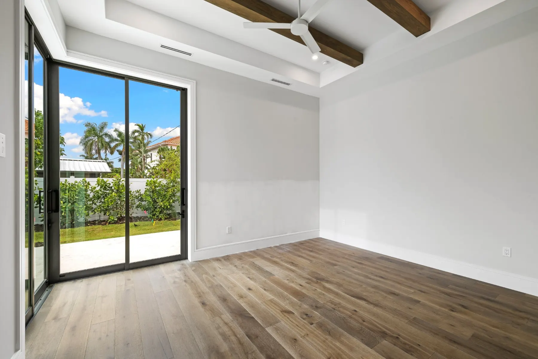 Bedroom with a sliding glass door to the patio and wood beams on the ceiling.