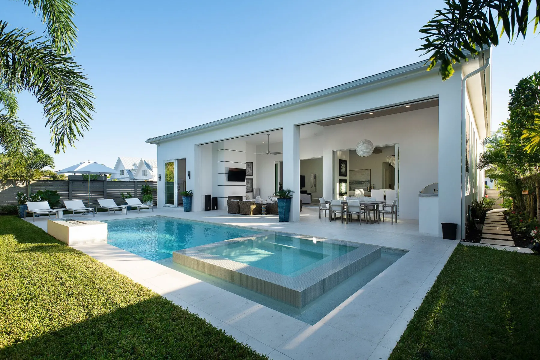 Rear of the home by day with a pool, raised spa and a covered lanai with outdoor seating and dining.
