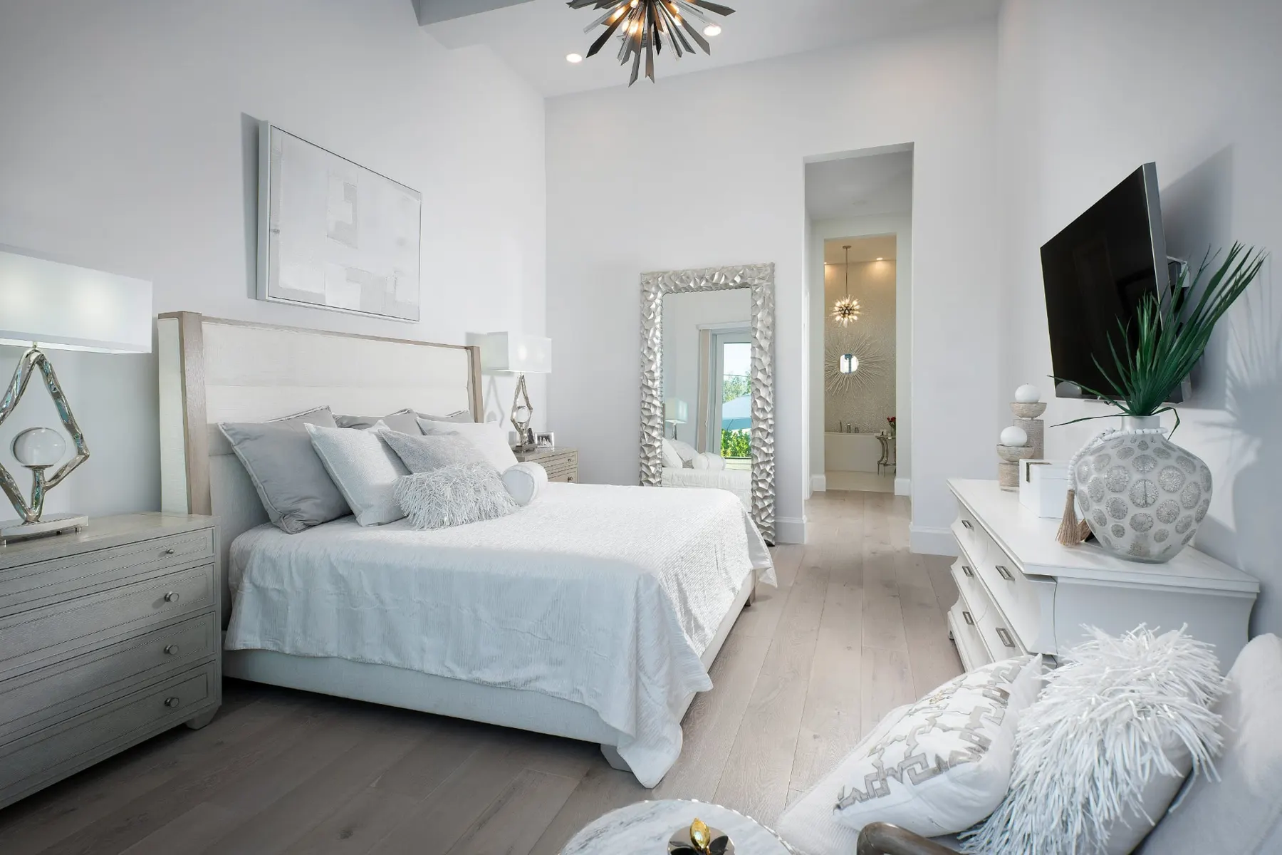 Primary bedroom with an upholstered headboard, a tray ceiling and a hallway leading to the bath.