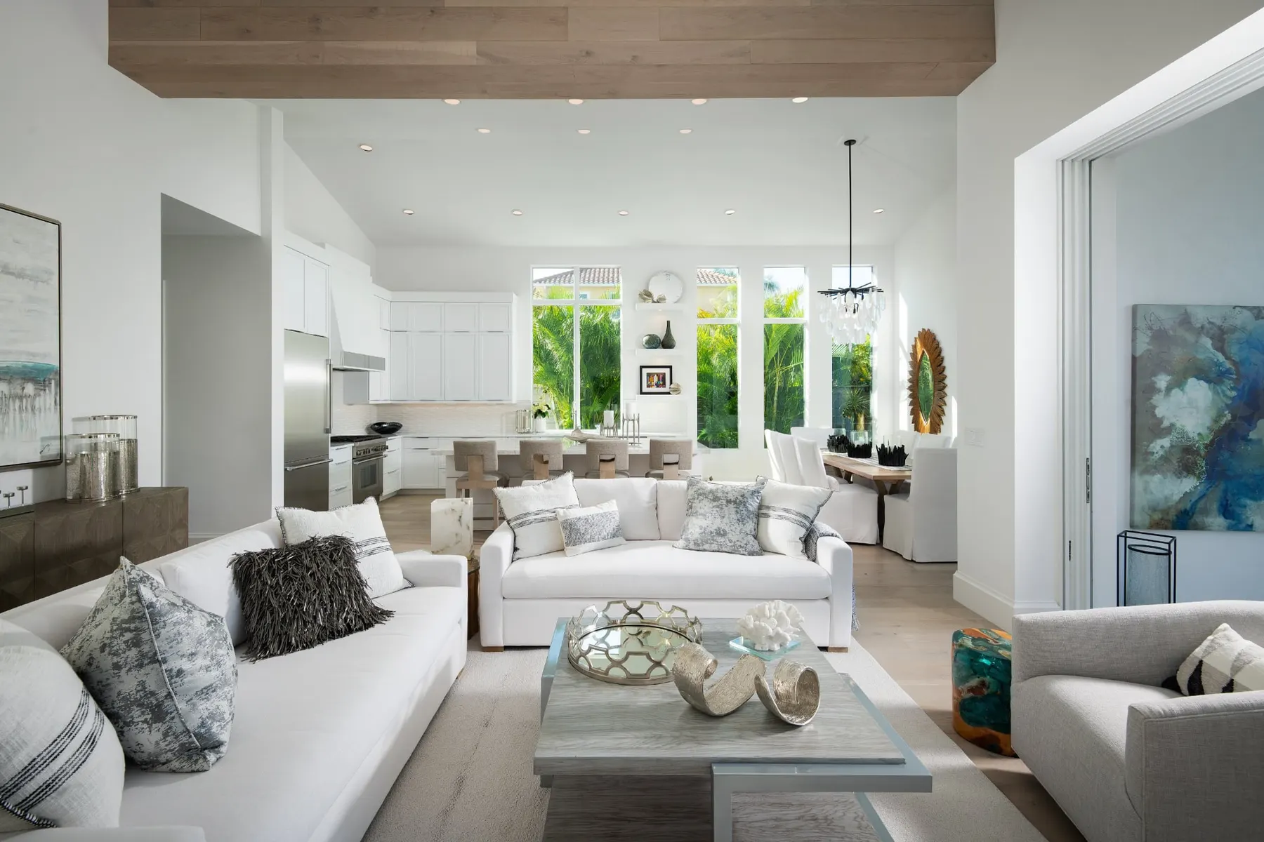 Living area opening to the kitchen and dining area under a vaulted ceiling with a wood-clad beam.