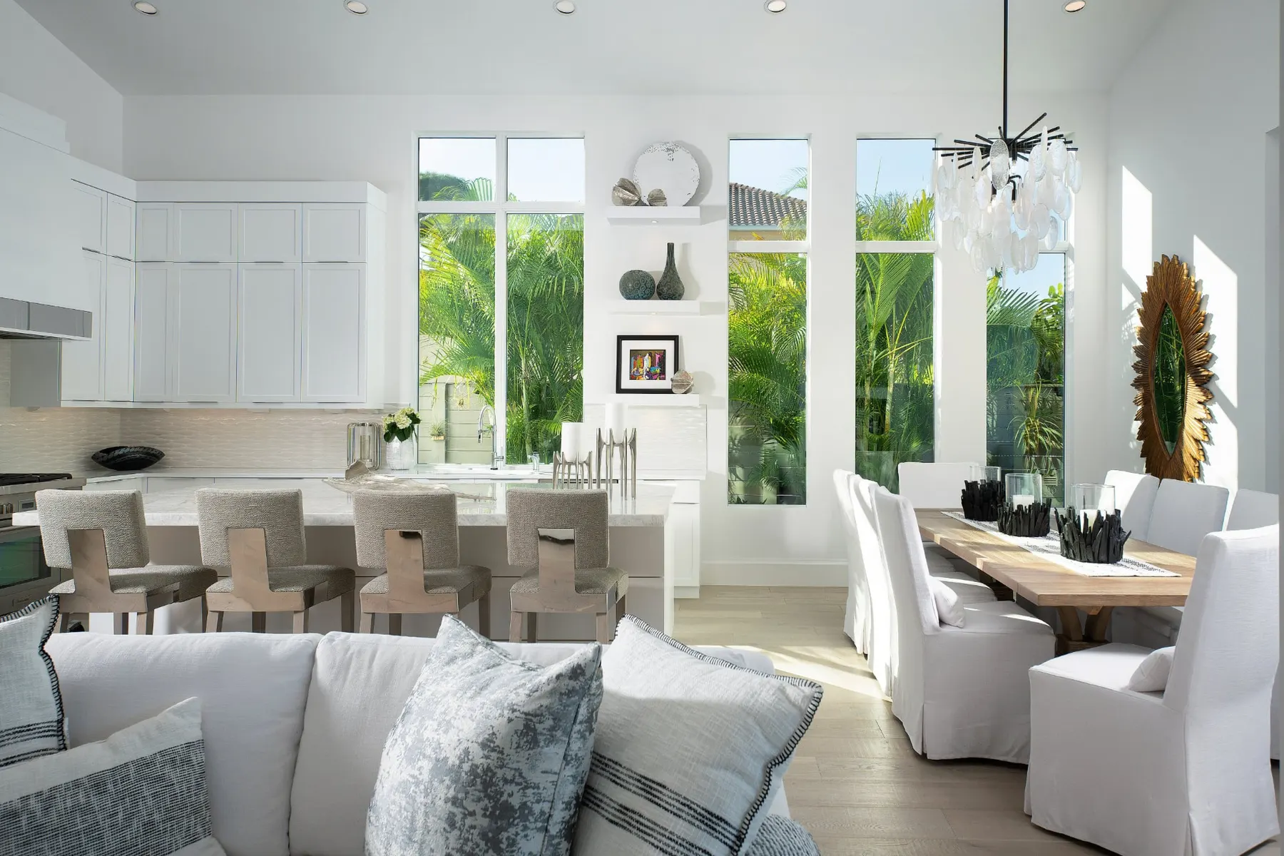 Kitchen island with four counter stools and tall windows, with the dining table to the right.