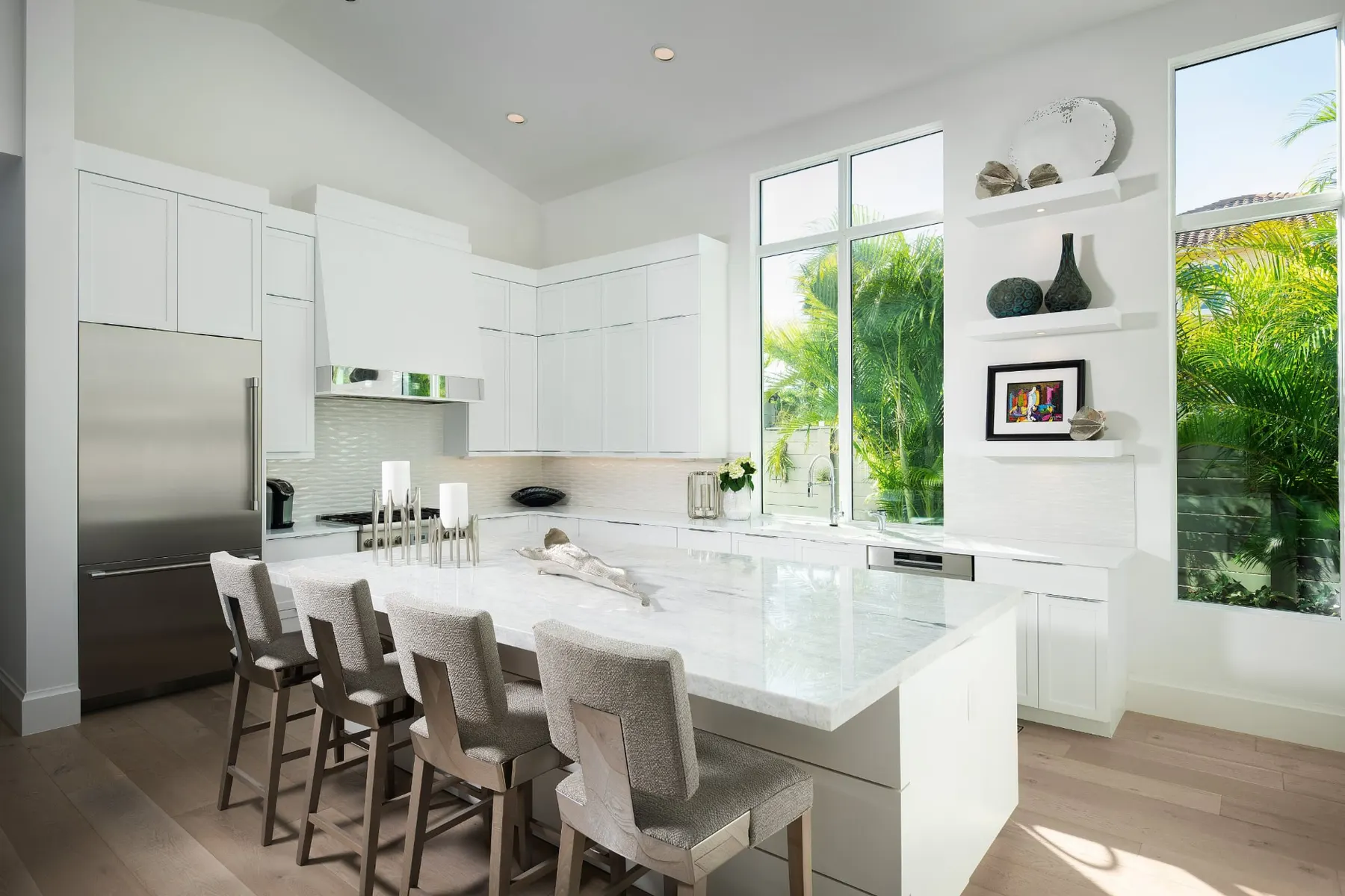 Kitchen with white shaker cabinets, a stone-top island, stainless steel appliances and floating shelves.