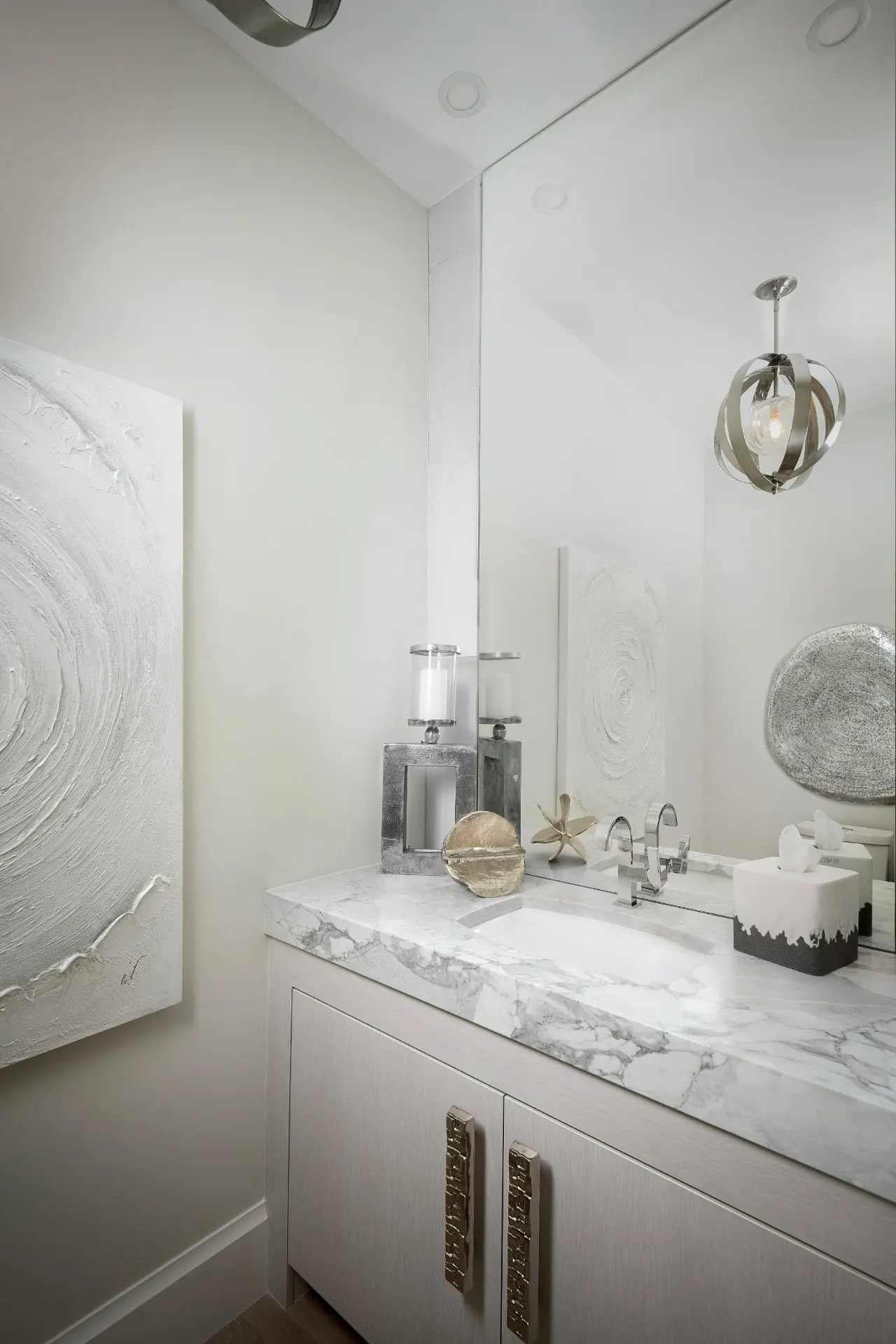 Powder room with a stone countertop, a floor-to-ceiling mirror and textured wall art.