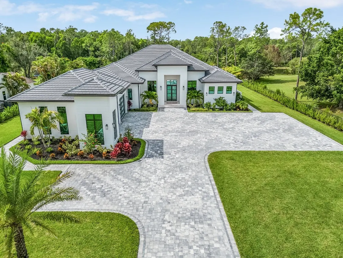 Front of the Oaks Estate Residence from above with a multi-hip tile roof, central entry and a paver motor court.