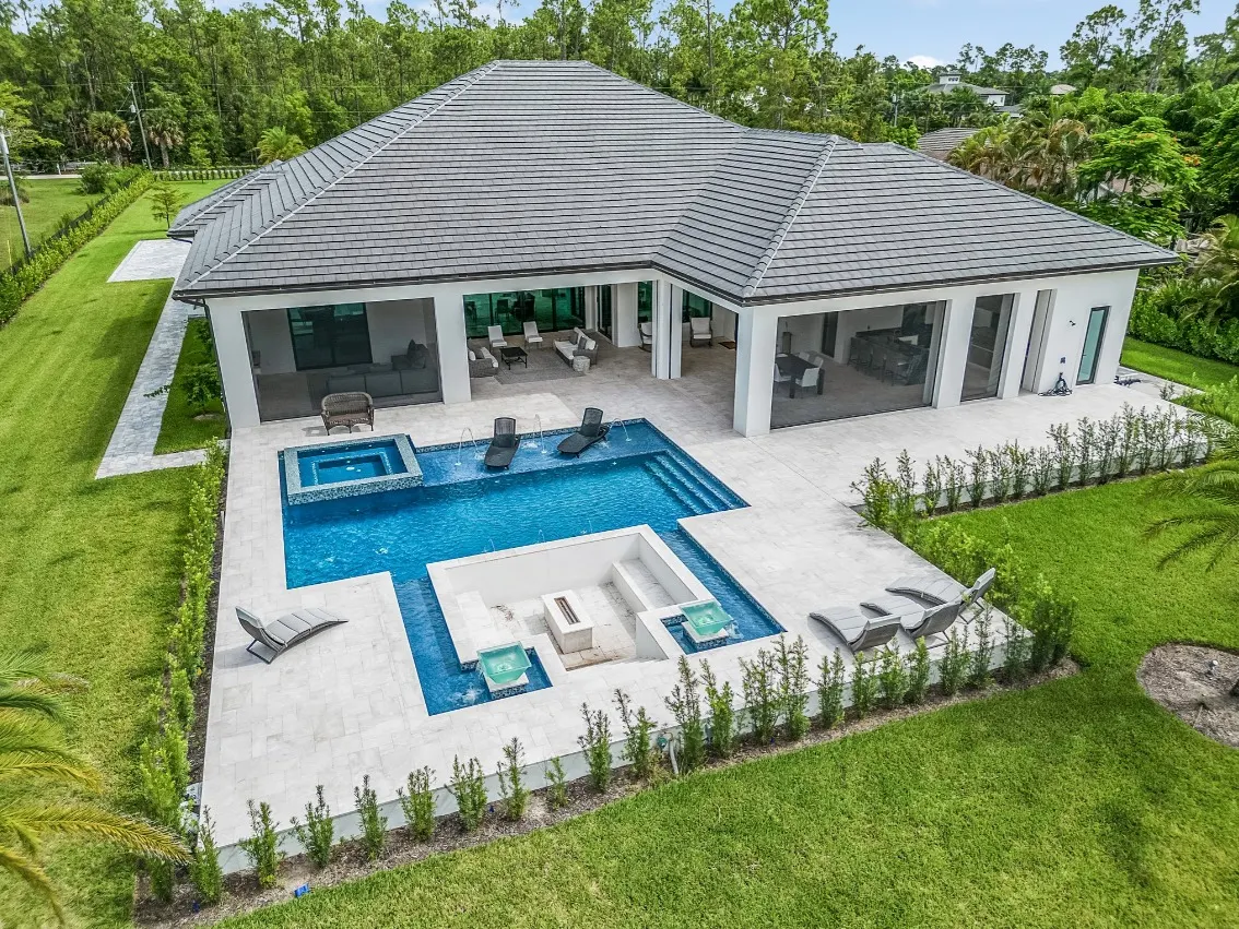 Aerial view of the rear with a covered terrace, pool and spa, and a sunken fire lounge.