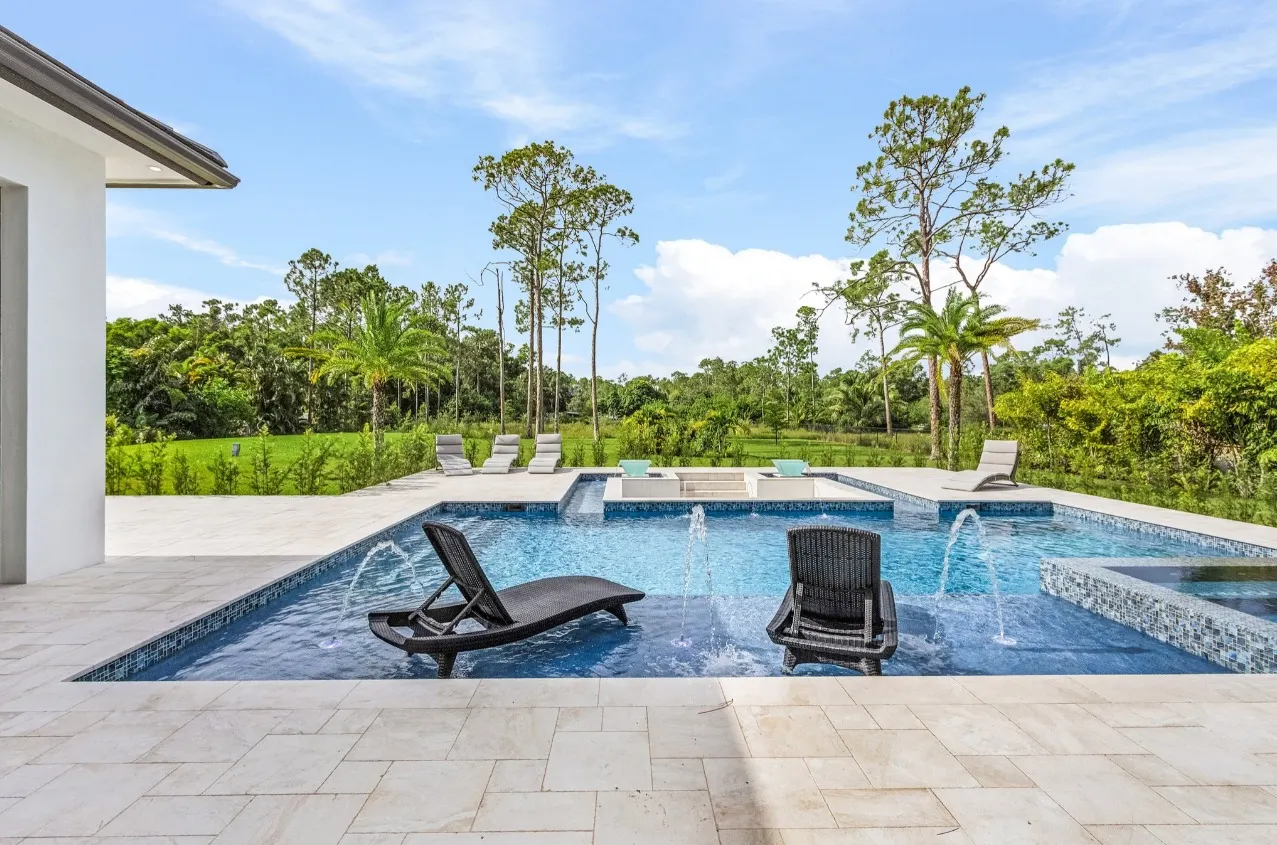Pool with in-water lounge chairs, water jets, a raised spa and a sun shelf with water bowls.