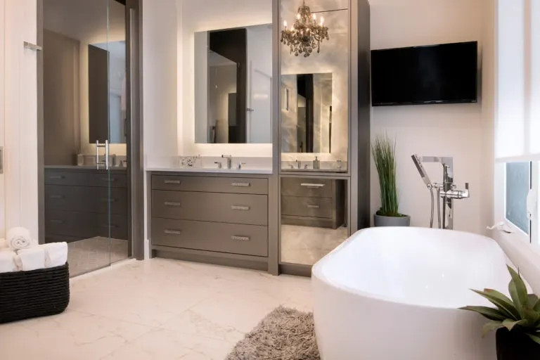 Bath with a freestanding tub, a floating vanity with lit mirrors and a glass-enclosed shower.